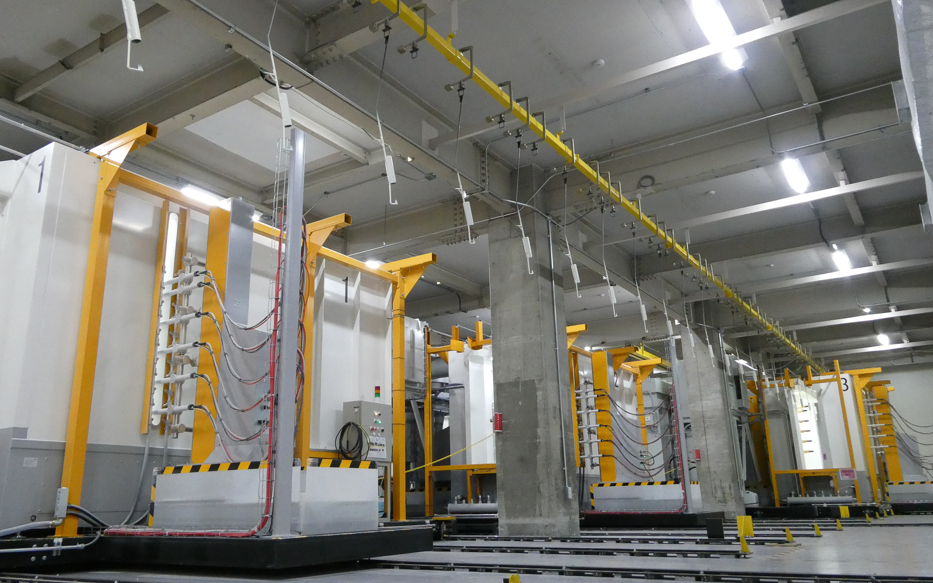 塗装しにくい部分にロボットアーム（左）で粉体塗装を吹き付けたあと、6個のスプレーを縦に並べた「レシプロ塗装機」（右）で一気に塗装していく