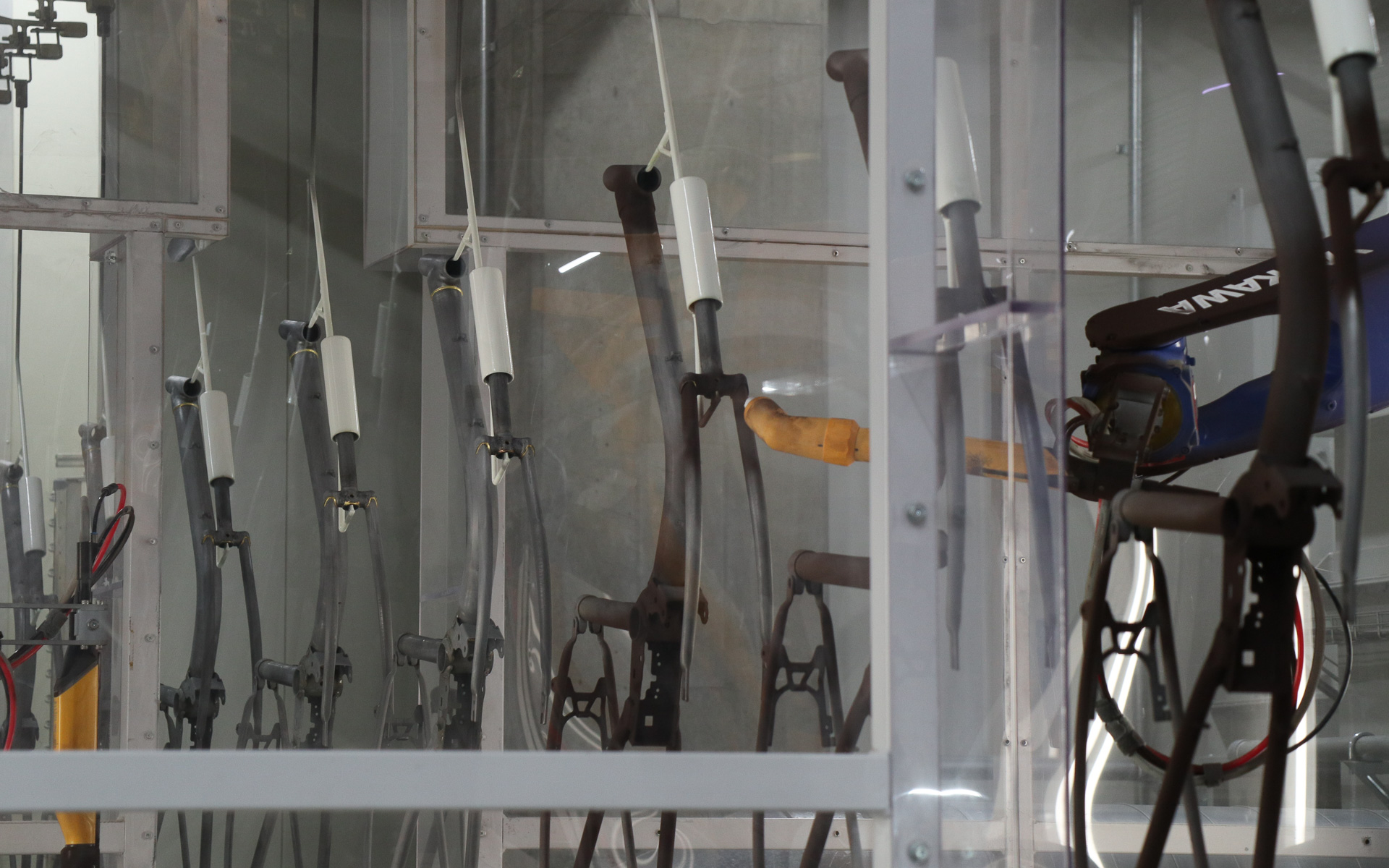 この先にあるレシプロ塗装機は両サイドから粉体塗装を吹き付けるため、前後フォークのように左右に分かれている部分や上下位置は塗装しにくいので、塗り残しが出ないようにロボットアームを使った事前塗装を行なう