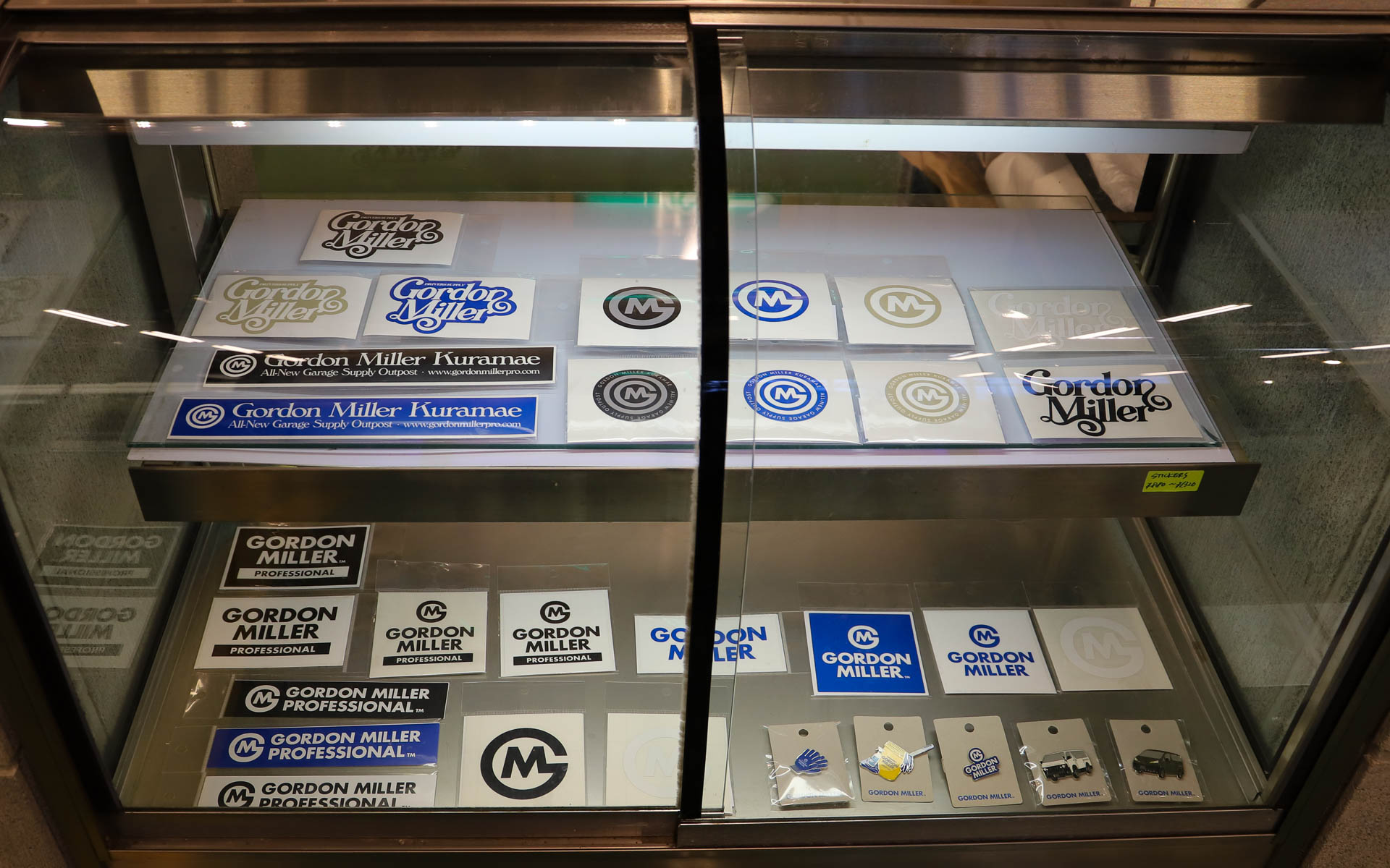 男女問わず着られるユニセックスなアパレルを展開。バッグやキャップといった小物や、コーデュラ素材のシューズ、ステッカー類もラインアップ