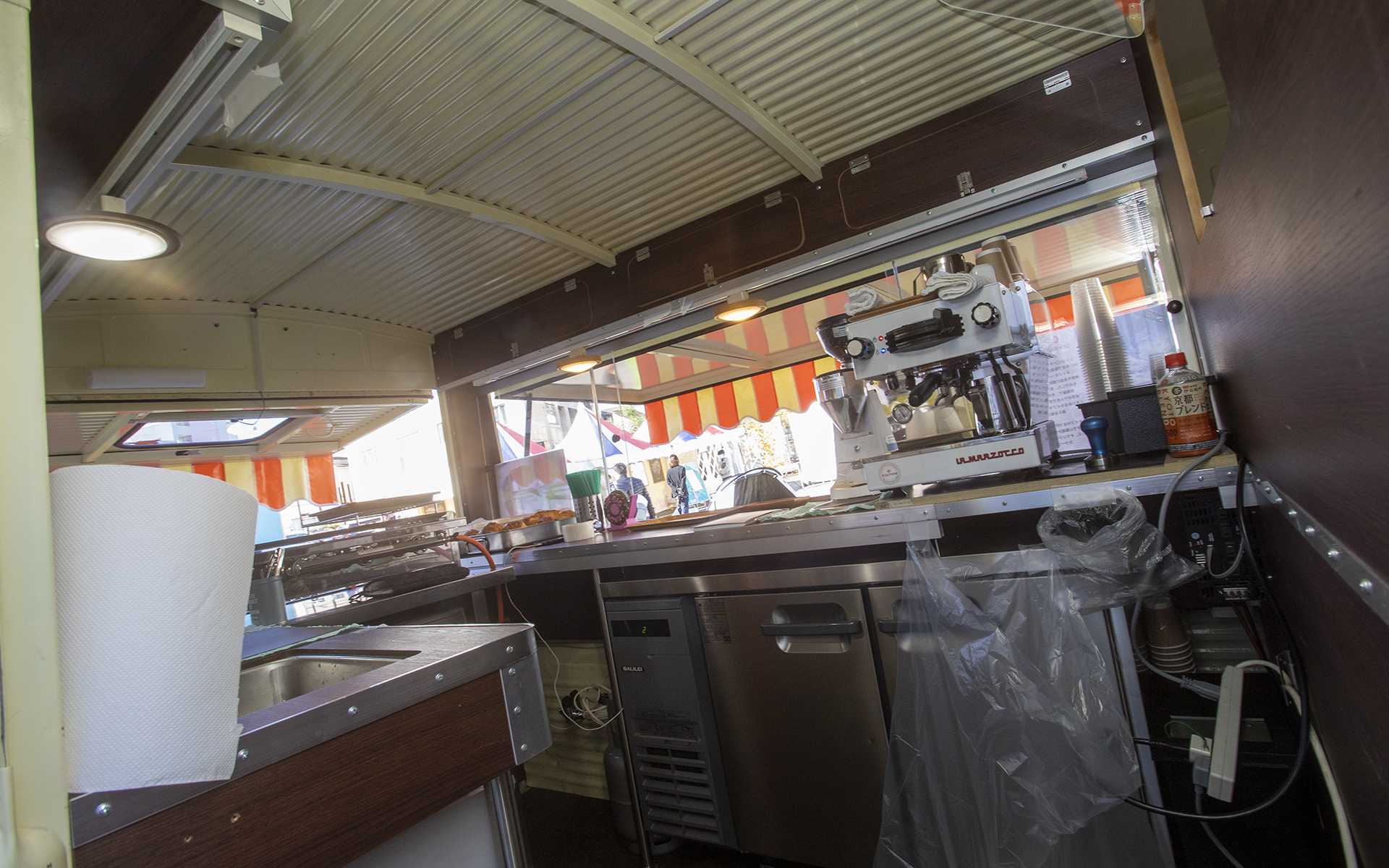 タイプHの車内を見せてもらった。キッチンスペースは広い。また、床が低いので天井が高く感じる、天井の波板は純正