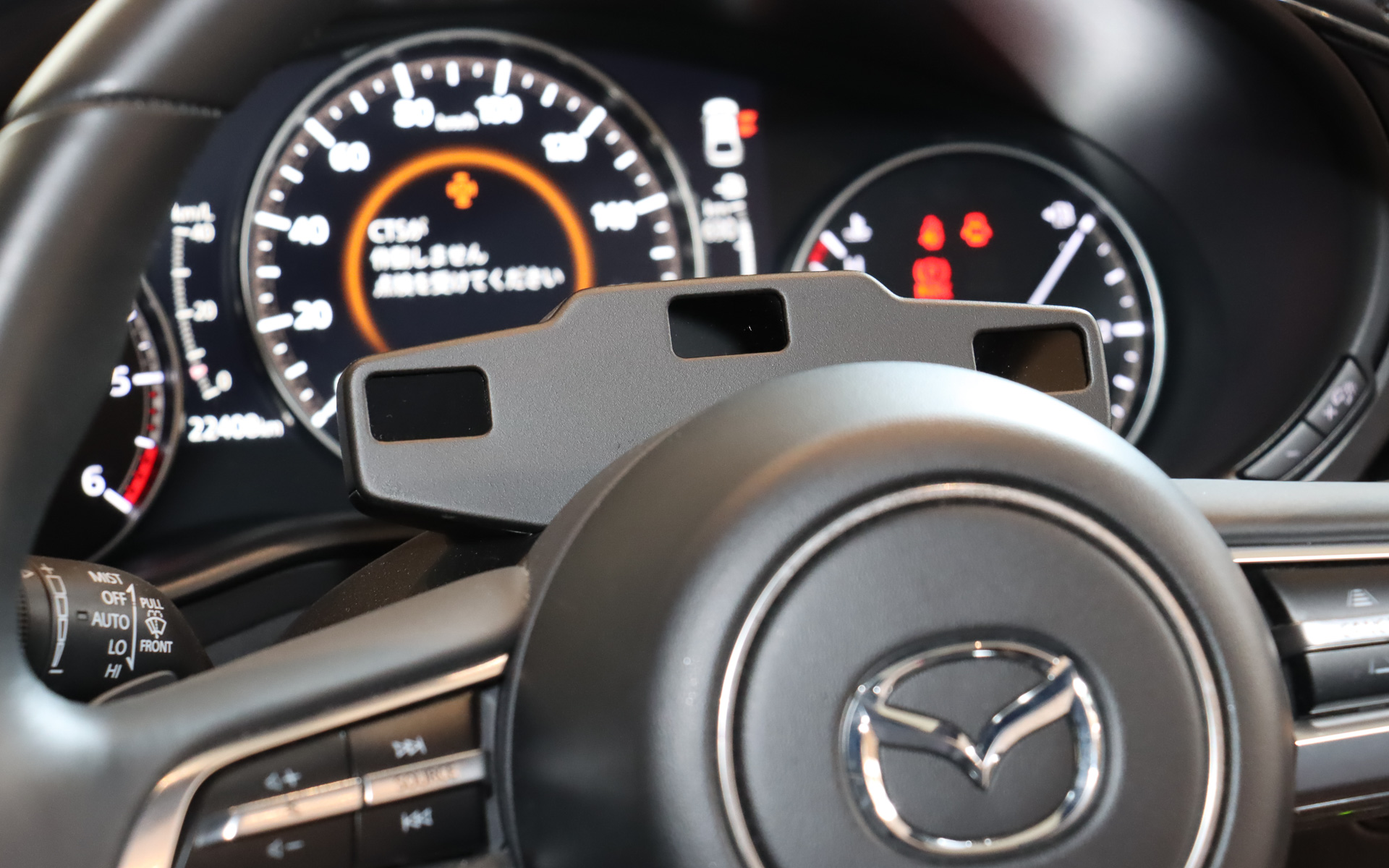 車内で追加されているのは、ステアリングコラムに設置されたドライバーの状態を検知するカメラと、実証実験のガイドラインで定められている緊急停止スイッチの2種類。i-ACTIVSENSEの「ドライバー・モニタリング」では、インパネ上に設置された「マツダ コネクト」のディスプレイ右上にあるカメラでドライバーの疲労や眠気を検知しており、マツダ・コ・パイロット・コンセプト2.0の市場投入時にはこのようなスマートな形での提供を目指している。しかし、マツダ・コ・パイロット・コンセプト2.0の「予兆検知」で利用しているパラメーターは多岐にわたることから、技術試作車両では新規のカメラを追加して対応している