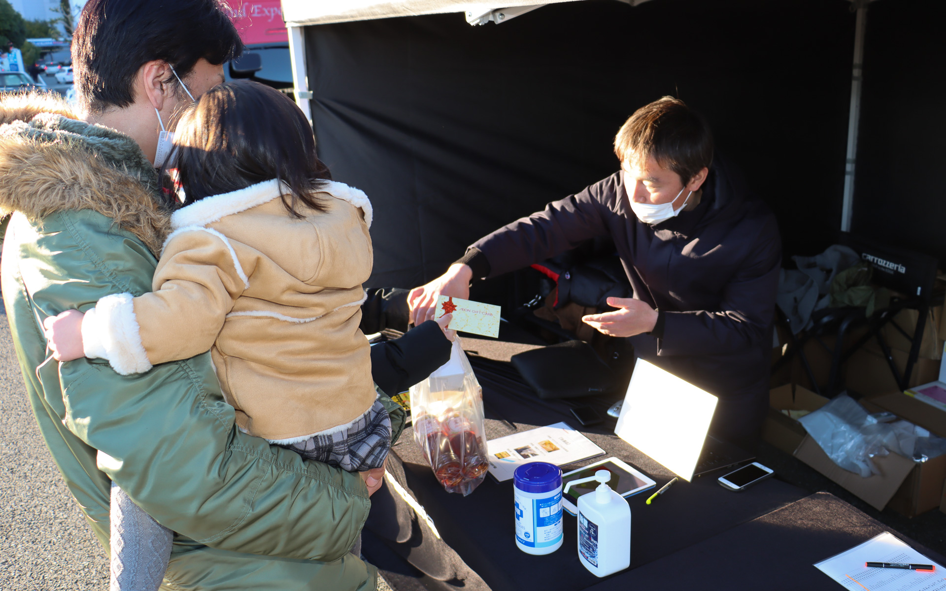 会場入りしてスクリーン前にクルマを駐車した後に特設テントで受付を済ませると、映画鑑賞のお供となるキャラメル味のポップコーンとトップバリュブランドの麦茶、上映開始までの時間にショッピングを楽しんでもらえる3000円分のイオンギフトカードが各参加者にプレゼントされた