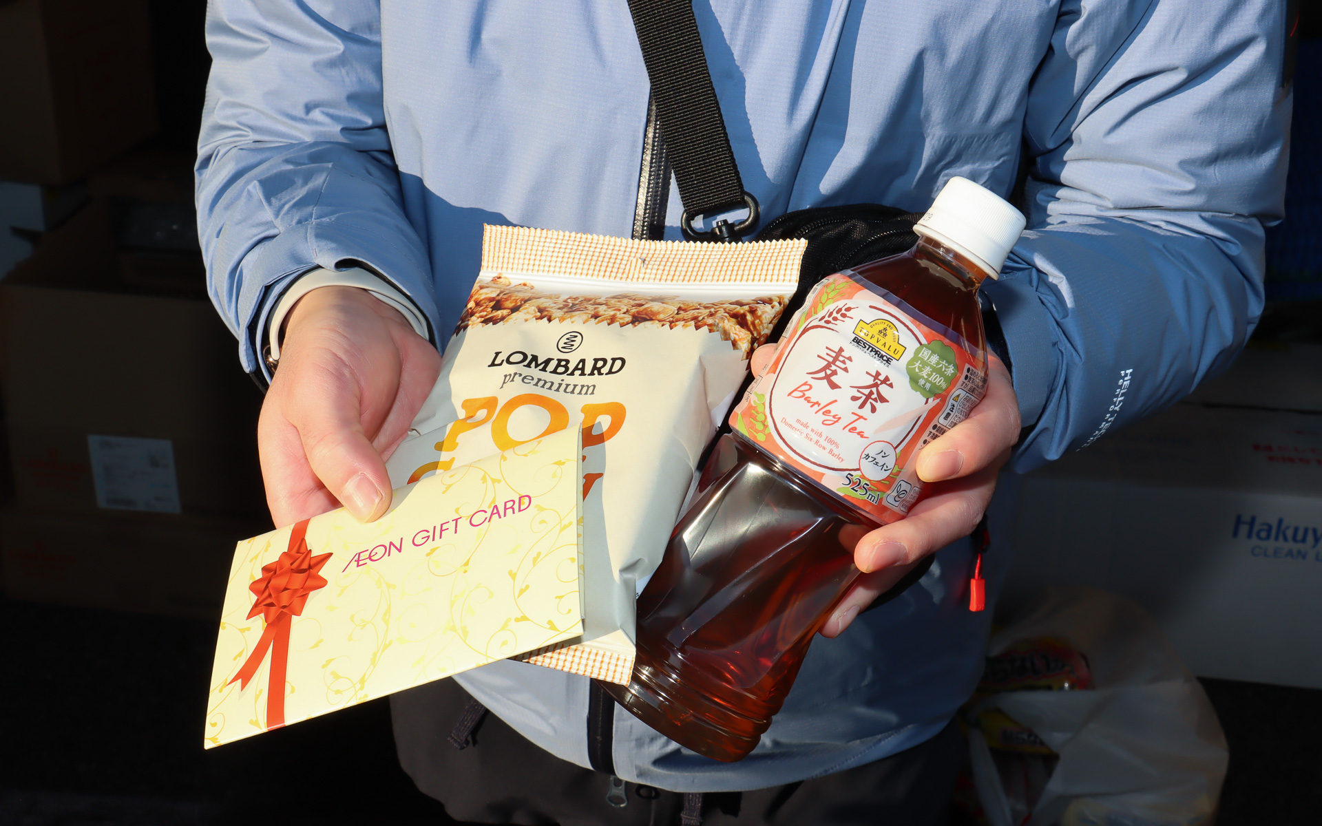 会場入りしてスクリーン前にクルマを駐車した後に特設テントで受付を済ませると、映画鑑賞のお供となるキャラメル味のポップコーンとトップバリュブランドの麦茶、上映開始までの時間にショッピングを楽しんでもらえる3000円分のイオンギフトカードが各参加者にプレゼントされた