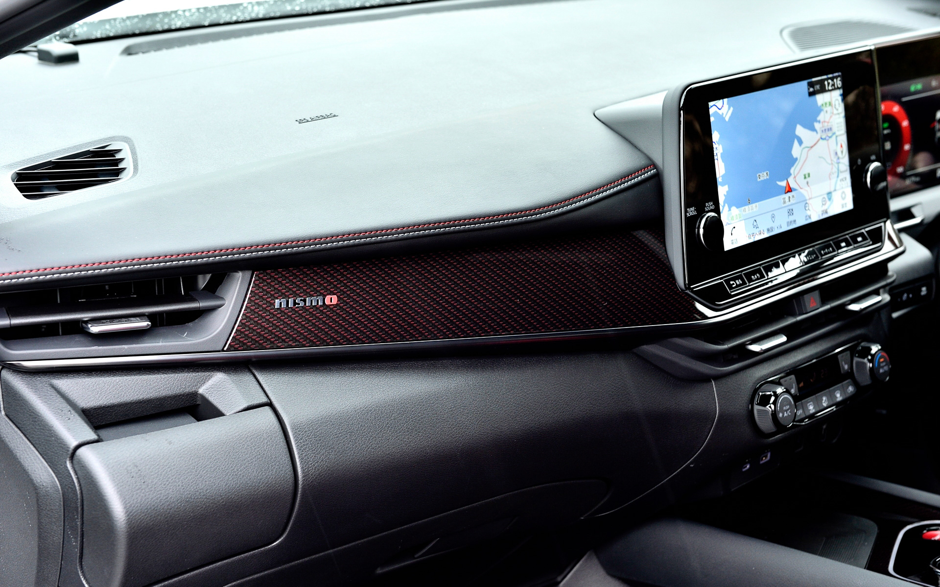 インテリアではダークトーン＆レッドアクセントの色調を特徴とし、専用ファブリックと合皮のコンビネーションを採用したシートはNISMOロゴの刺繍やレッド/グレーのコンビネーションステッチにより、スポーティな室内空間を演出。オプション設定のレカロ製スポーツシート（39万6000円）ではシート形状にこだわり、クルマとの一体感を向上させた