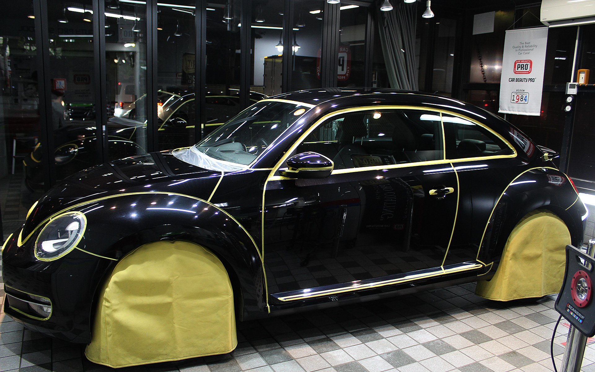 マスキング作業。パネルの継ぎ目、ライト、突起物などの境目にすべて施す。安全に研磨作業を行なうための重要な工程となる