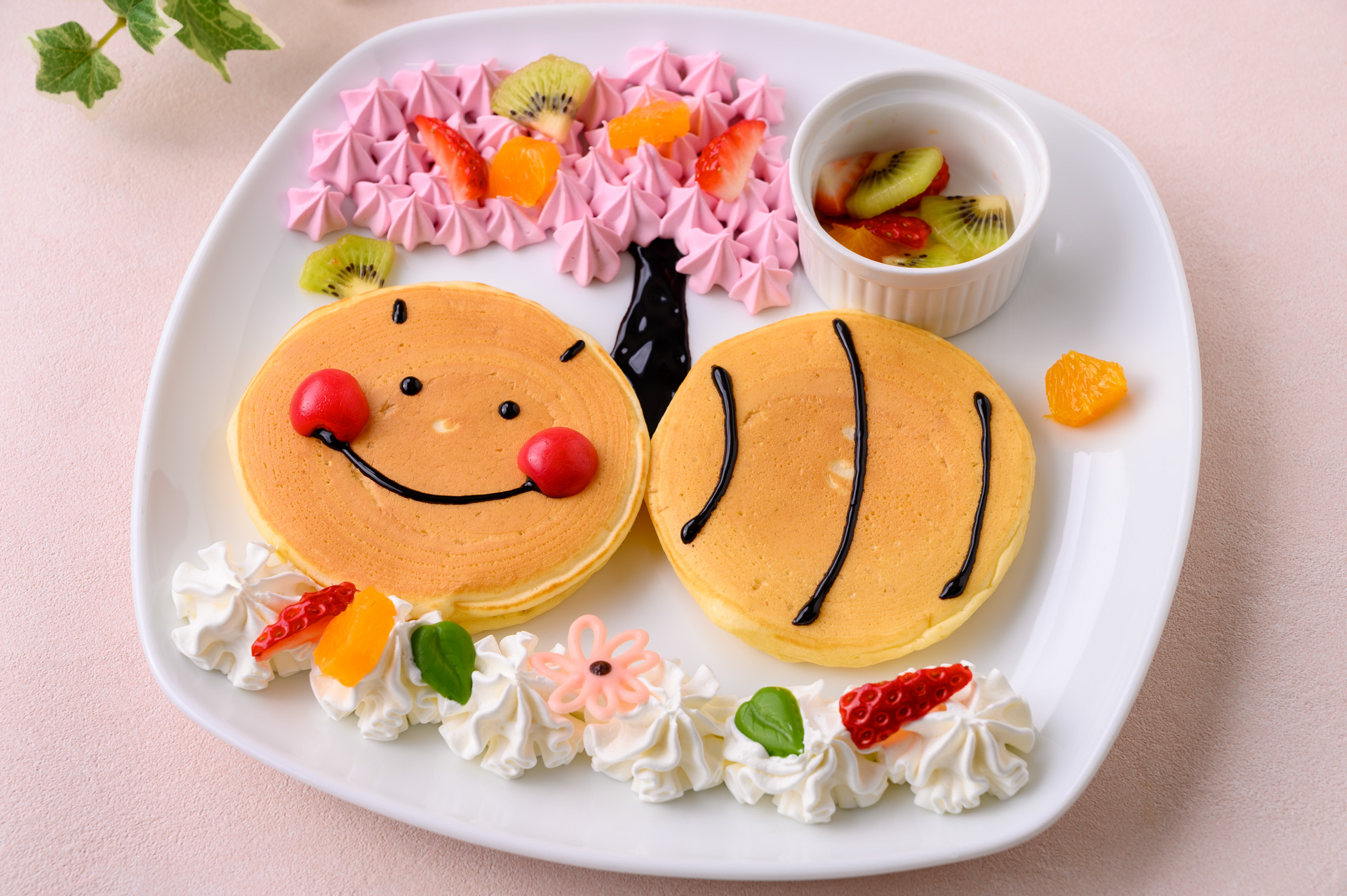 2022年3月5日～6月30日の期間限定販売される「ぶんぶんの花咲けフルーツの木パンケーキ」店舗：ぶんぶんのパンケーキやさん、価格：850円。桜の花びらをイメージした生クリームの上に、お花のチョコレートやフルーツをトッピングして完成するパンケーキ