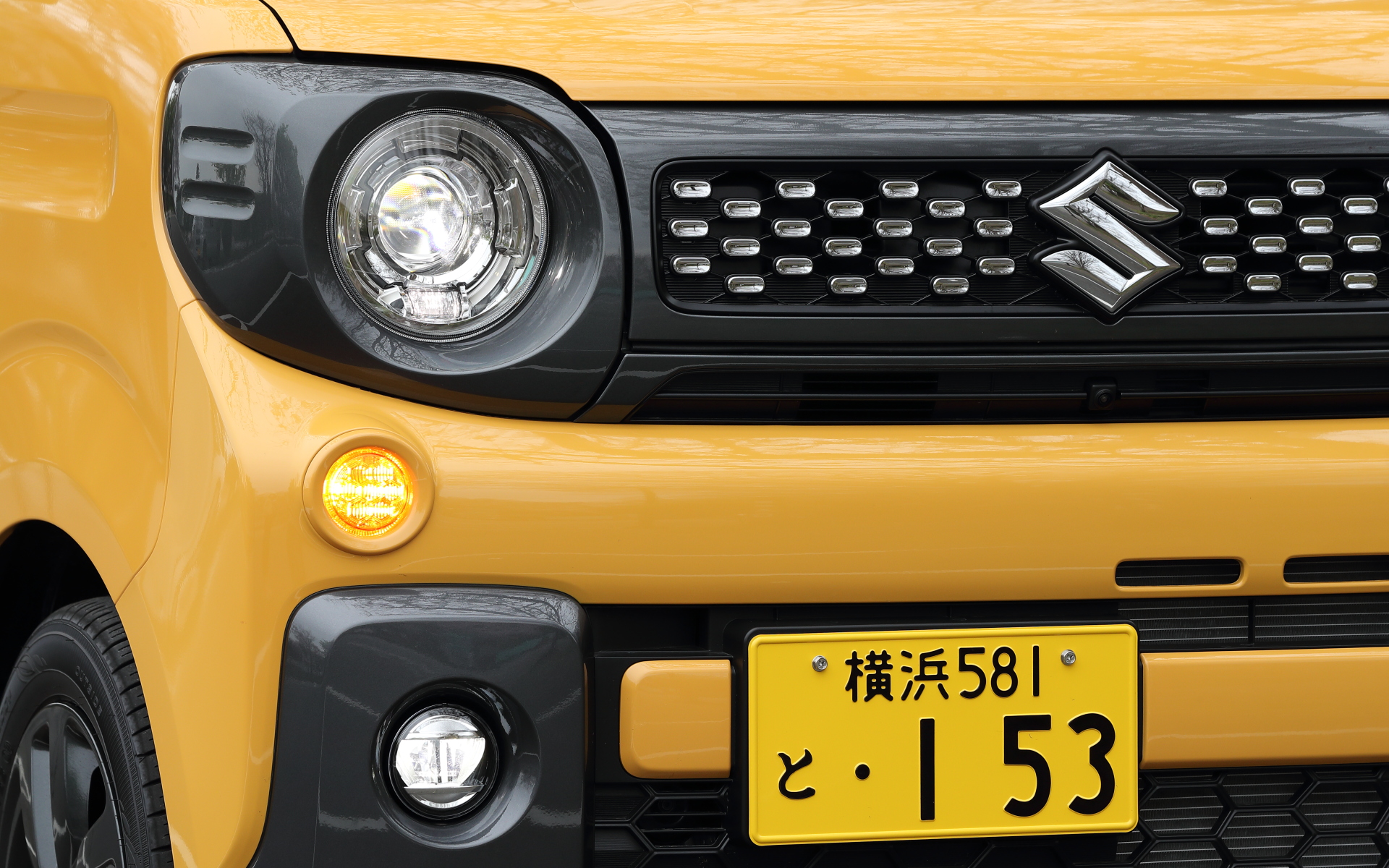 スズキの軽SUVをイメージさせる丸目ヘッドライトと、周囲のガーニッシュによる個性的なデザインが特徴