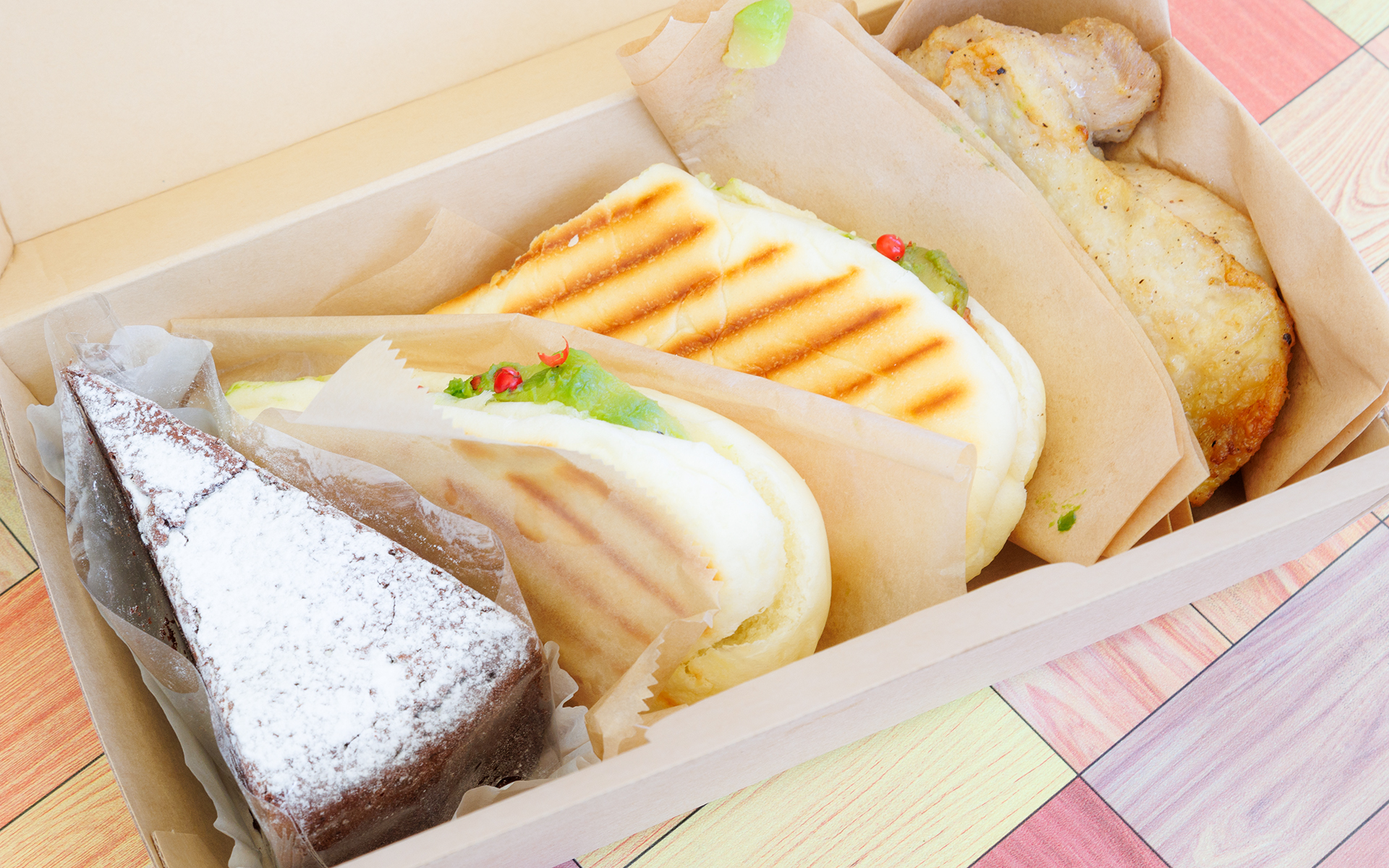 参加者に提供されたランチボックス。パニーニとグリルチキンに、デザートにはチョコレートケーキ