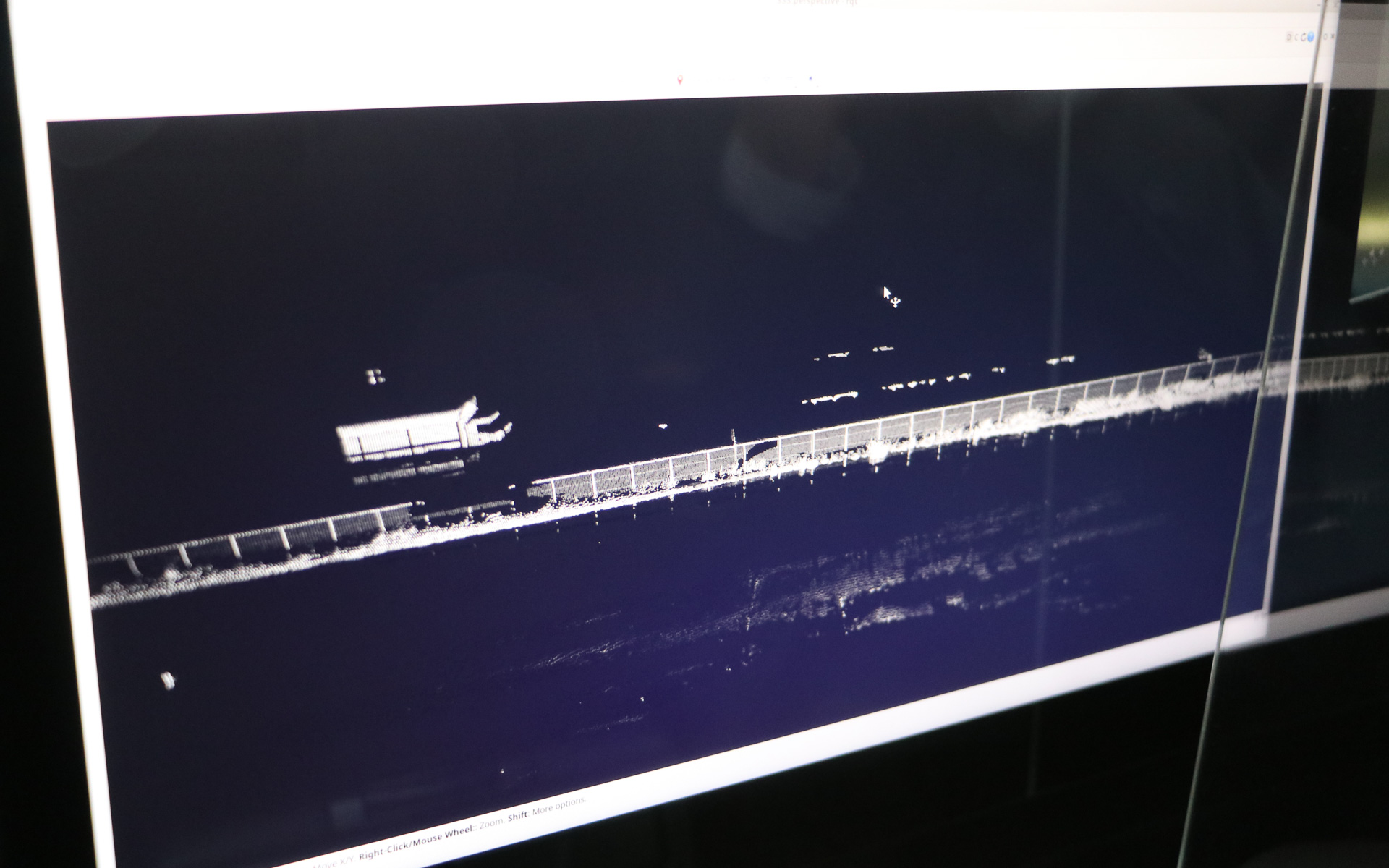 駐車場の金網フェンスと、その向こう側の高速道路を走るトラックも鮮明に補足