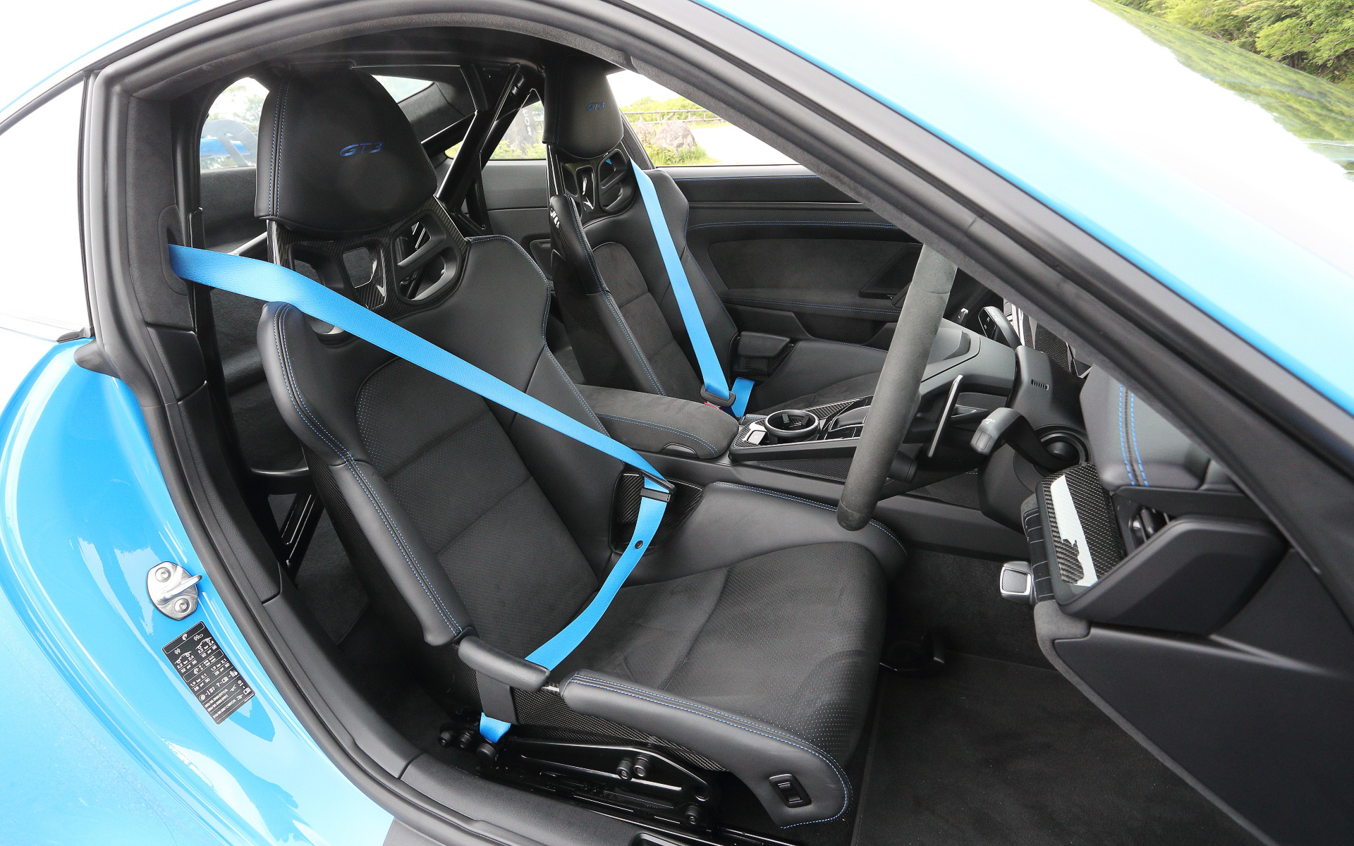 無償オプションの「クラブ スポーツ パッケージ」に含まれるスチール製ロールケージを装備して2名乗車仕様となる911 GT3のインテリア。メーター中央に最高回転数10000rpmのタコメーターをレイアウトし、タイヤ空気圧インジケーター、油圧、油温、燃料残量、水温といったサーキット走行に不可欠な情報を得ることが可能。フルバケットシートやシャークブルーカラーのシートベルトなどはオプション設定
