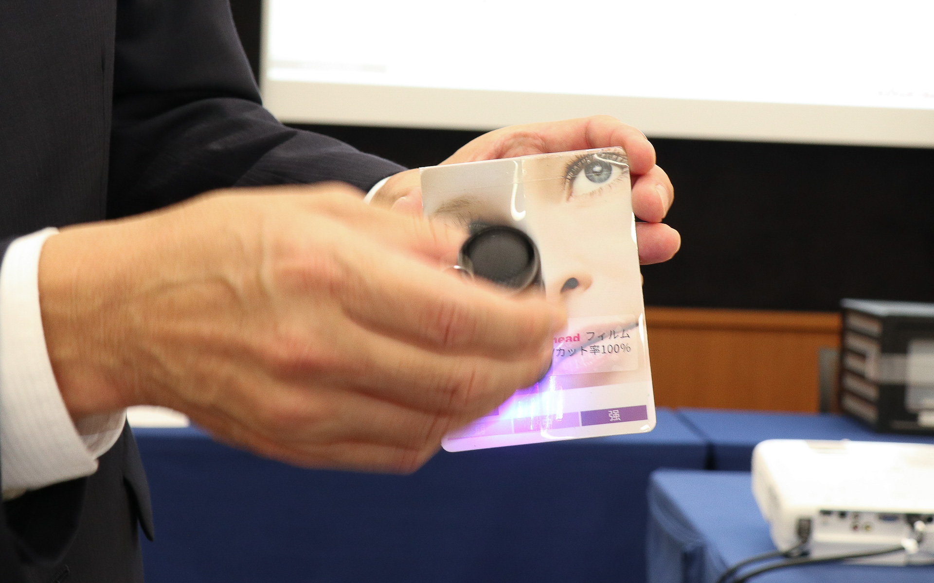 UVを吸収して変色するシートを貼った写真パネルの上に、他社製品とahead製品のウィンドウフィルムを被せてブラックライトで照らしていく