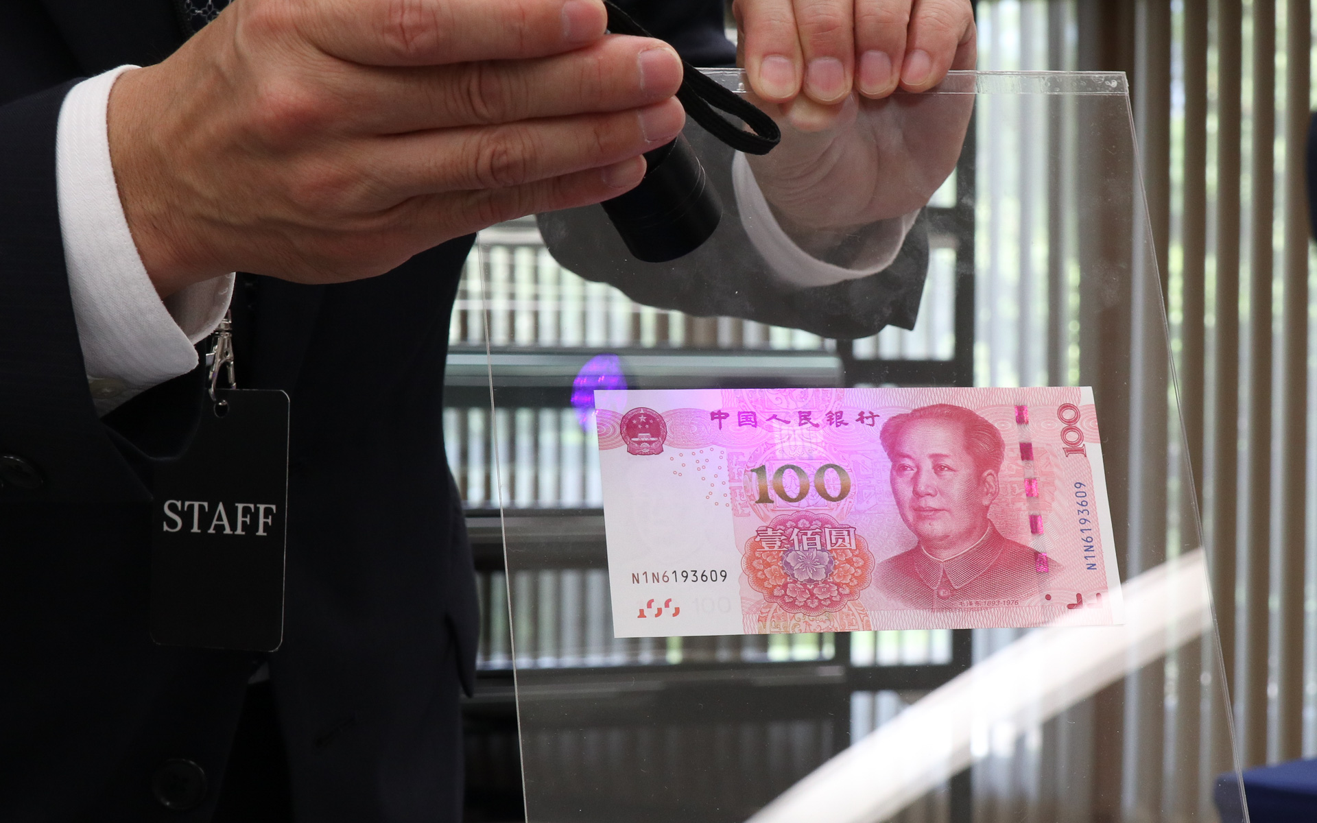 中国の人民元を使ったデモ。偽造防止策の1つとして、中央にある100の数字の上に、ブラックライトのUV光を反射して100の数字が浮かび上がる仕組みが施されている