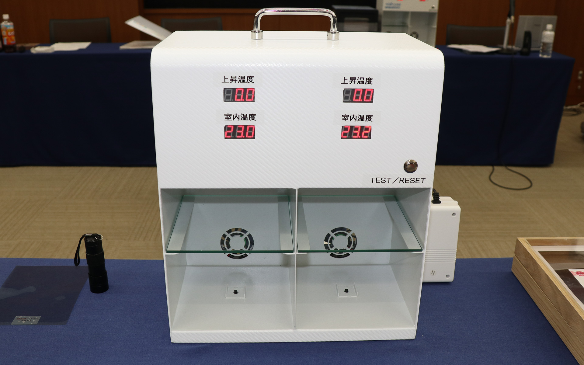 IRカット率のデモでは専用の計測器を使用。左右に仕切られた計測スペースの下側に温度センサーが設置されて「上昇温度」「室内温度」を計測。実際に手を入れて温度の違いも体感できる