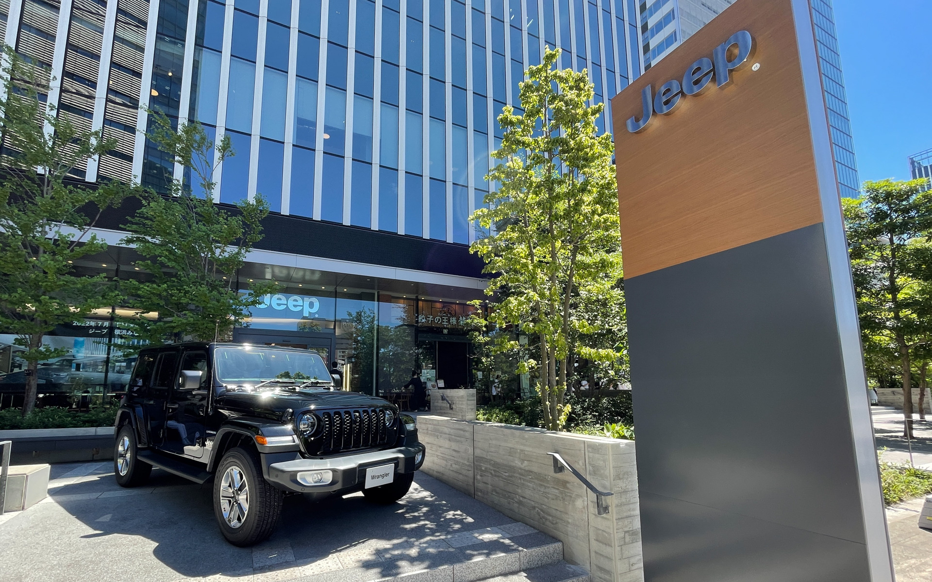 複合施設の1階にあるショールームは、道路面より数段上がった位置にあり、ジープの新CIであるブラックとウッドパネルを外観にまとった趣のあるデザインを採用。内照式ジープロゴのブランドバッチサインとディーラーネームサインを正面に配し、また敷地内のパイロンサインにより道路からの視認性を高めた