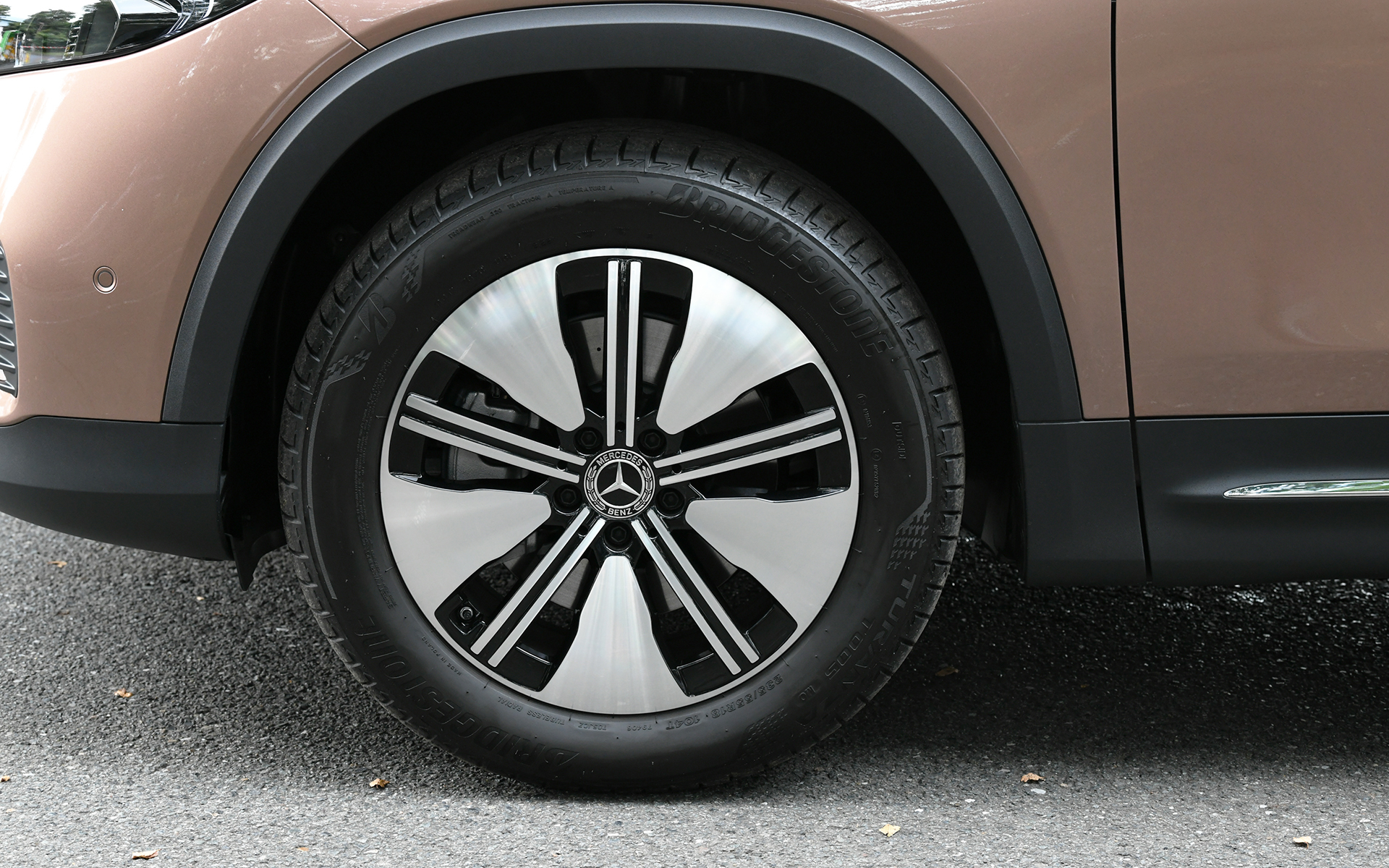 都市型SUVの洗練されたプロポーションを持つEQBでは、中央にスリーポインテッドスターを配したブラックパネルグリルを採用。一見するとGLBと共通のスタイルに見えるが、前後エプロンの形状変更が行なわれるとともに、空力特性や風切り音の低減を考慮したドアミラー、ボディ下側を流れる空気を整流するために刷新したアンダーボディパネル、ルーフスポイラーなどさまざまな個所で空力の最適化が行なわれた。EQB 250の足下は18インチアルミホイールにブリヂストン「トランザ T005」（235/55R18）を組み合わせる。充電については6.0kWまでの交流普通充電と、100kWまでの直流急速充電（CHAdeMO規格）に対応