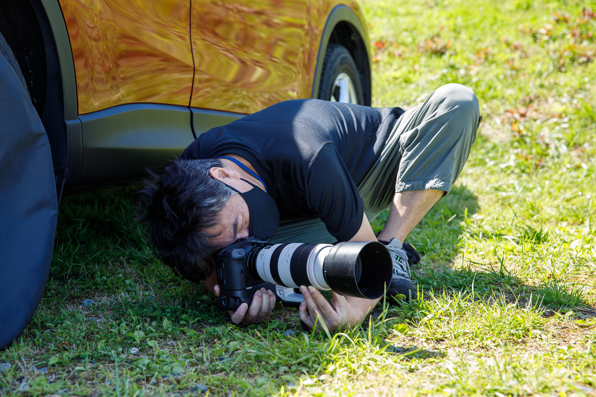 小学生時代に「オリンパスペンEE-3」を手にしたことから写真好きに。クルマはもちろん鉄道、飛行機といった乗り物系のほか、プライベートでは風景や動物といったネイチャー系の撮影も。デジタル化は2001年発売の「キヤノンEOS-1D」から。写真は望遠レンズを使い地面すれすれのローアングルから狙う安田カメラマン。氏によると望遠レンズを使うのは「自動車の形が歪まず車体の形が自然に見える」ため。またローアングルから撮ると車体の下に向こうが見えて「安定感だけでなく遠近感も強調されて写真が生き生きとしてくる」という