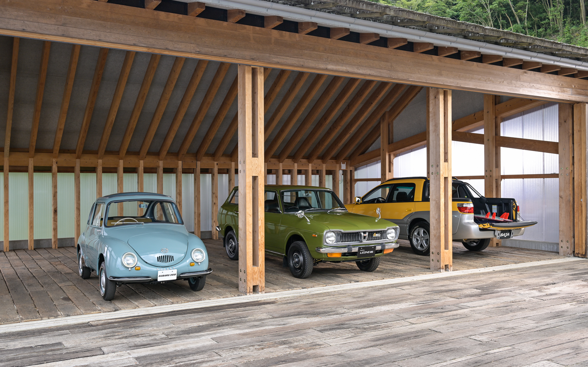 都会を離れた場所から紹介、後方には歴代の主要なスバル車があり、日本未発売のスバル「バハ」も見られる