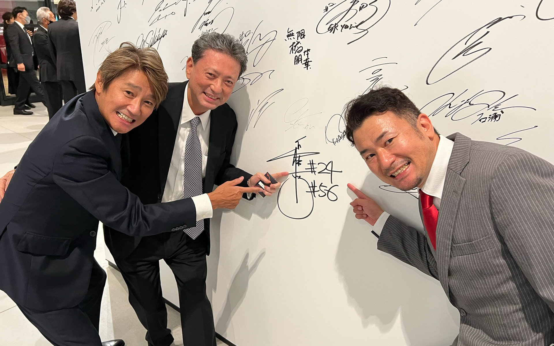 レセプション後、富士モータースポーツミュージアムの壁に参加者がサイン。横浜ゴム社長 山石昌孝氏（中央）、近藤真彦監督（左）、坂東正敬監督（右）は、タイミングを合わせてサインをしていた。ミュージアムに行った際は探してみてほしい