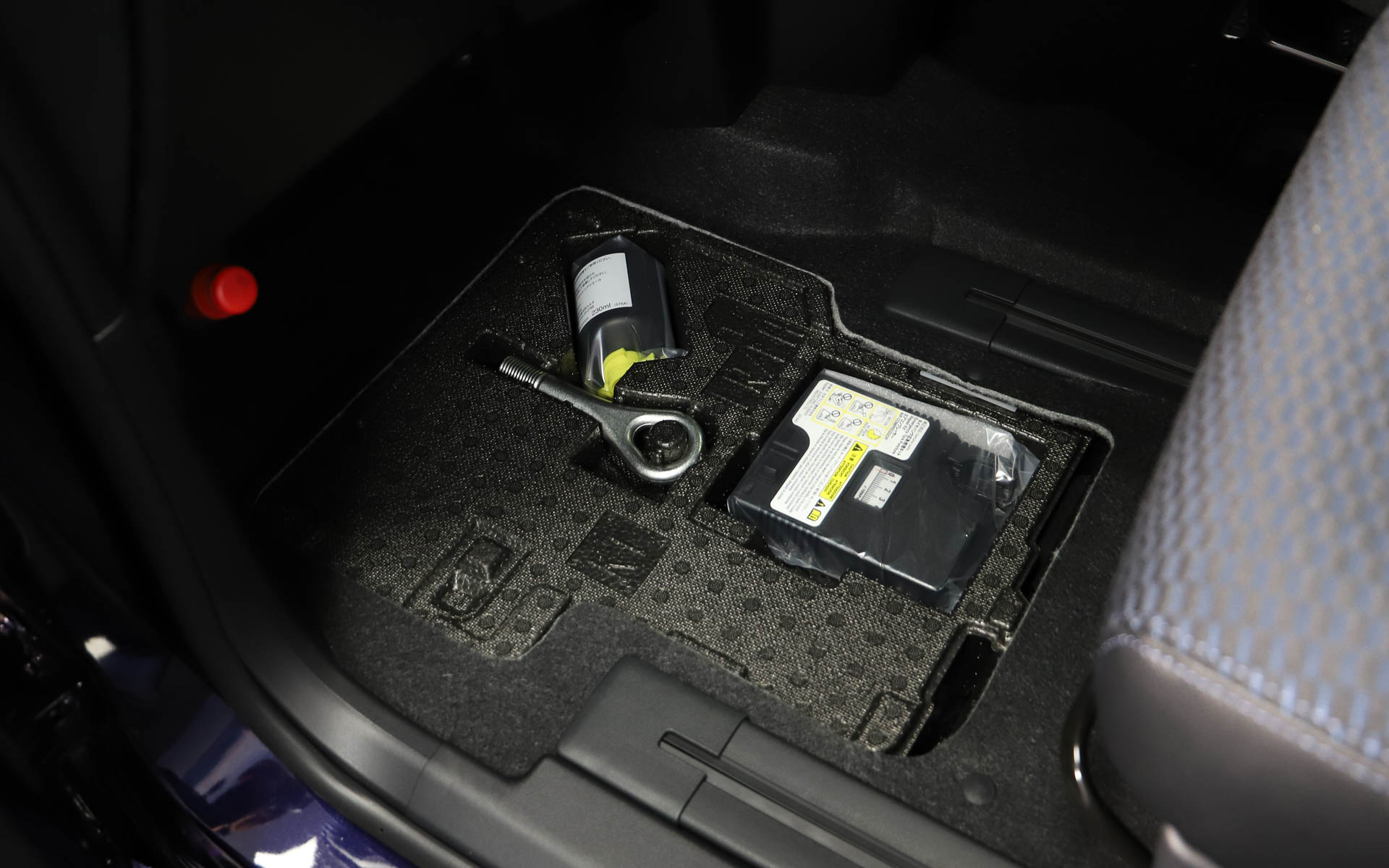 パンク修理キットは助手席足下のデッドスペースに移動。ラゲッジ下の収納を広く使えるようにした