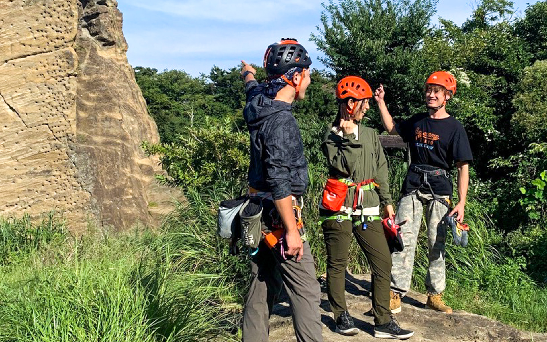 ホンダアクセスのデザイナー、山田さん（右）と、アウトドアスポーツ系のロケも数多く手がけているというインストラクターさん（左）の手ほどきを受けて、ロッククライミングの装備をつけ終わったところ。ハーネスは必ず、サイズが合うものを装着してほしいとのことでした。腰につけている赤いバッグには、体操選手が手につけるような滑り止めの粉が入っていて、山田さんは登っている途中で何度もつけ直していました。が、私はそんな余裕は全くありませんでした（笑）