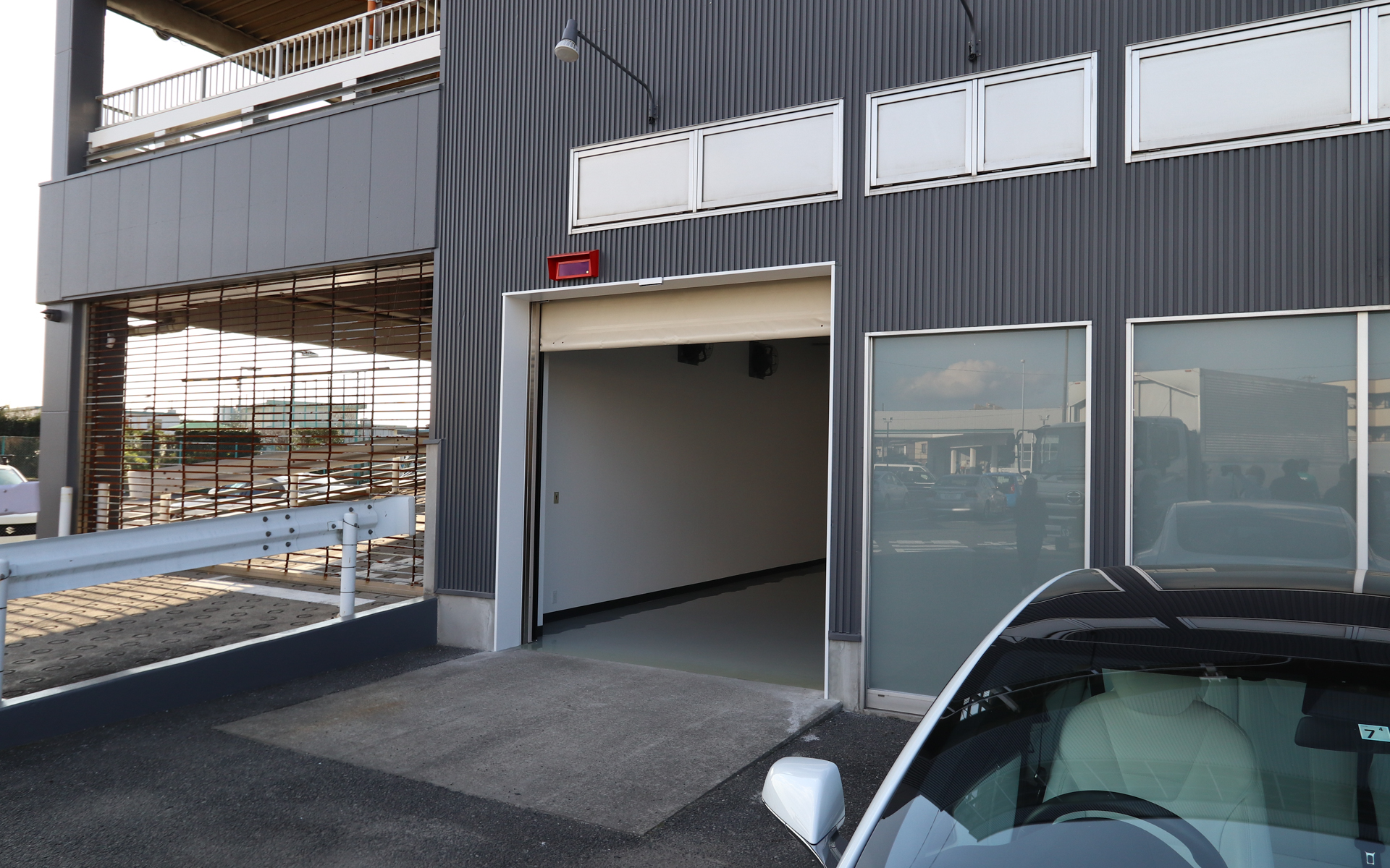 出口はこちら。後方に見えるのが2階、屋上に向かうスロープ。2階がデリバリー（納車）のスペースになるという