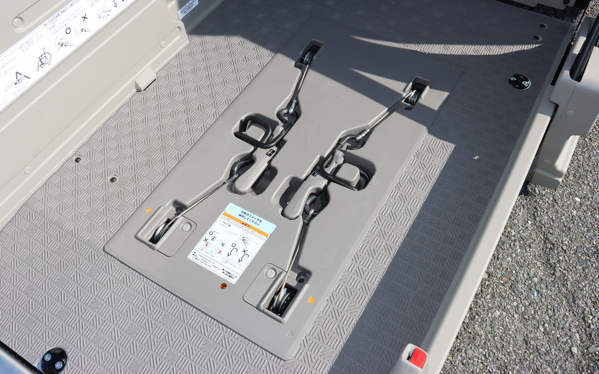 2月にマイナーチェンジされた「キャラバン チェアキャブ」。車両後方の車いす固定装置が改良され、電動リフターに車いすを固定するフックを一新。軽量化されたほか、車いすの前後2か所で固定する場合にはボタンを押すだけのワンアクションで分離できるアイデアを採用。扱いやすさを高めて短時間で固定作業を完了できるようにしている。なお、ロックボタンにはラチェットハンドルのソケット固定を解除するプッシュボタンの仕組みを参考にしているとのこと