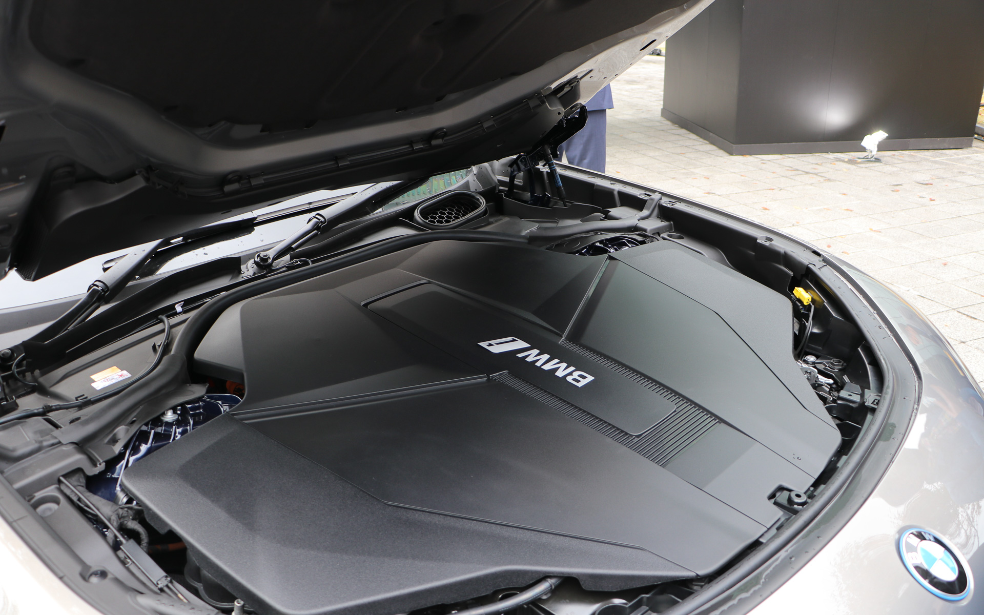 ボンネットを開けるとICE（内燃機関）搭載モデルの設定もあるとのことでエンジンを搭載していないがエンジンカバーが装着されていた。BEVのi7では電気関係の配線がエンジンルームに収められている