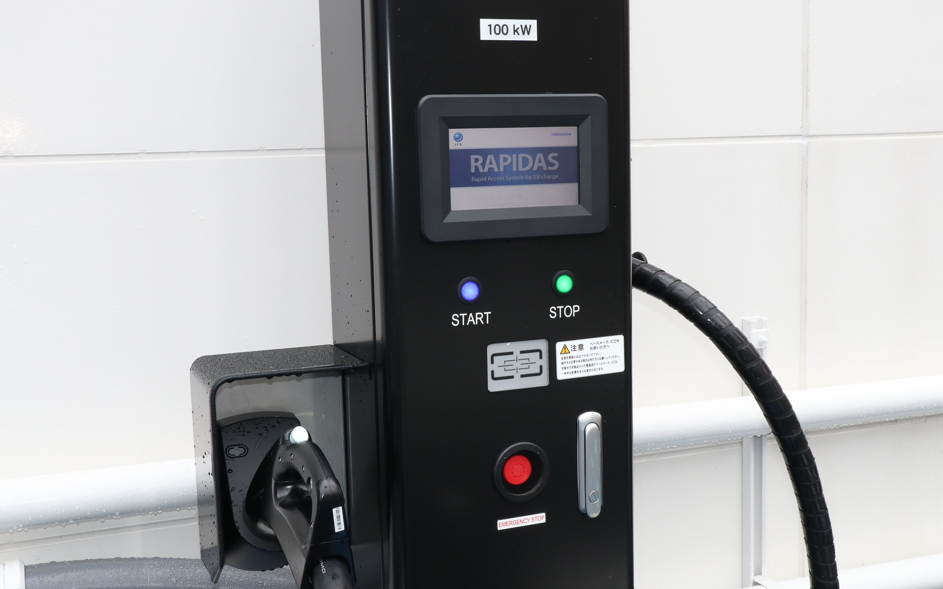 来客用の駐車場に急速充電の充電口を2口分用意。採用されているJFEテクノス製の蓄電池内蔵型EV用急速充電器「ラピダス」は、定格100kWの最大出力に対応するものの、リチウムイオンバッテリの蓄電池を併用することで3相200V受電での急速充電を実現。料金が安い低圧受電契約で待ち時間の短い急速充電を可能としている