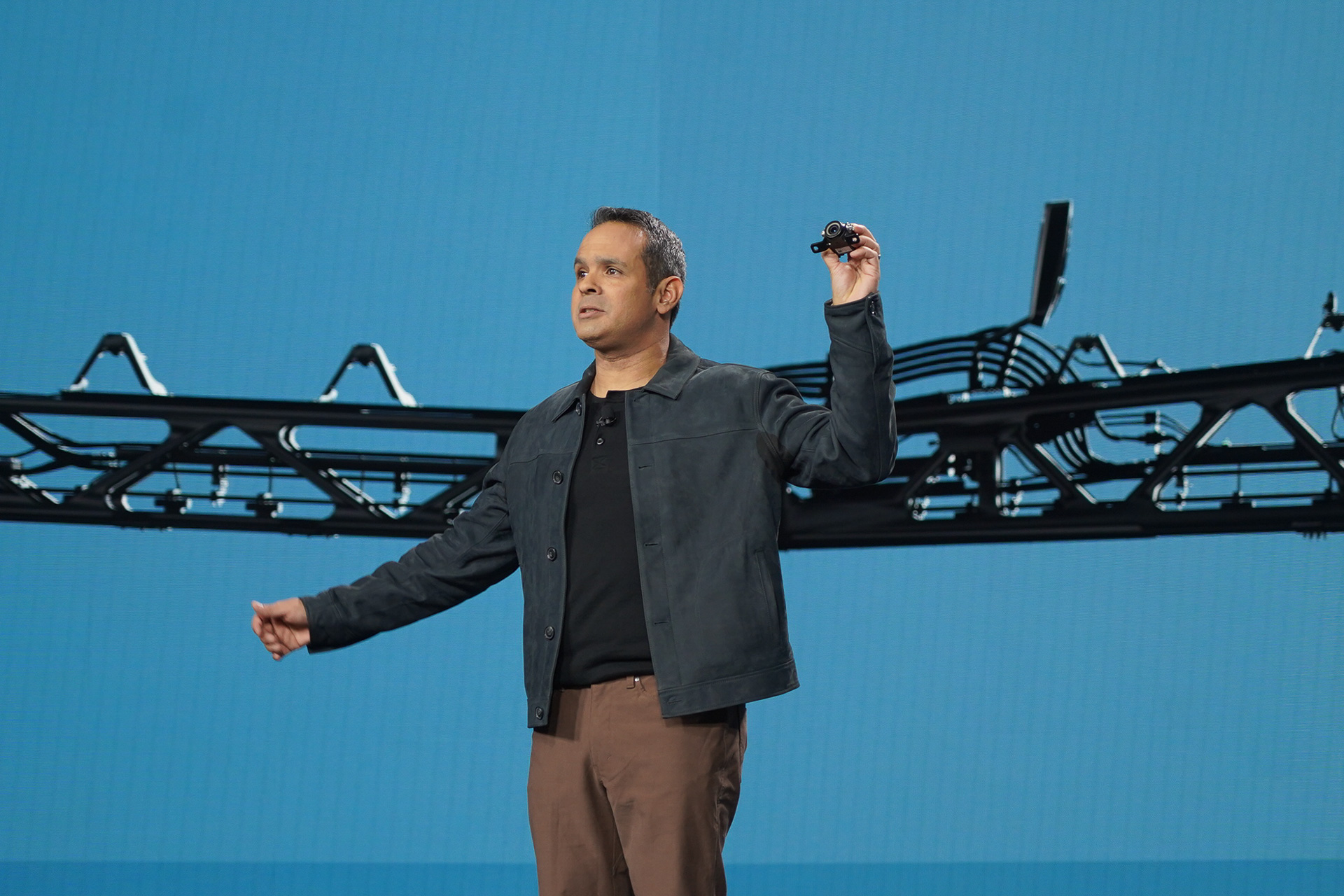 ジョンディア 先端技術開発ディレクター ジュリアン・サンチェス氏。左手に持っているのが同社の自動運転トラクターに搭載されているカメラ