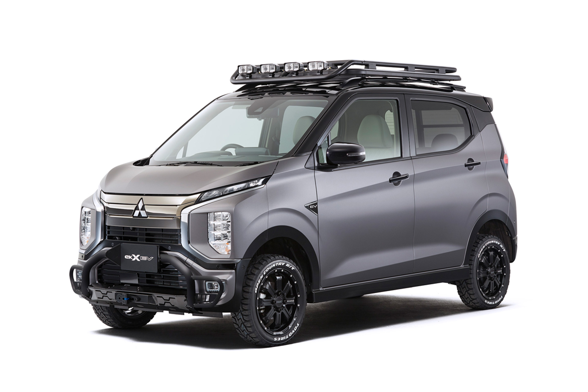 eKクロス EV Smooth×Tough（スムーズ バイ タフ）。eKクロス EV Smooth×Toughは、2022-2023日本カー・オブ・ザ・イヤーをはじめとするカーオブザイヤー3冠を受賞したeKクロス EVをベースとし、EVの滑らかで力強い走りをそのままに、SUVテイストをよりいっそう高め行動範囲を広げてくれるカスタムカー。ボディカラーは上質なマットグレーメタリック（ボディ）とブラックマイカ（ルーフ）の2トーンカラーとし、フロントグリルガードやオールテレーンタイヤを装着。さらにリフトアップすることでオフローダースタイルとしている。また、ルーフラックやリアラダーなどを装着し、アウトドアレジャーでの使い勝手を高めた