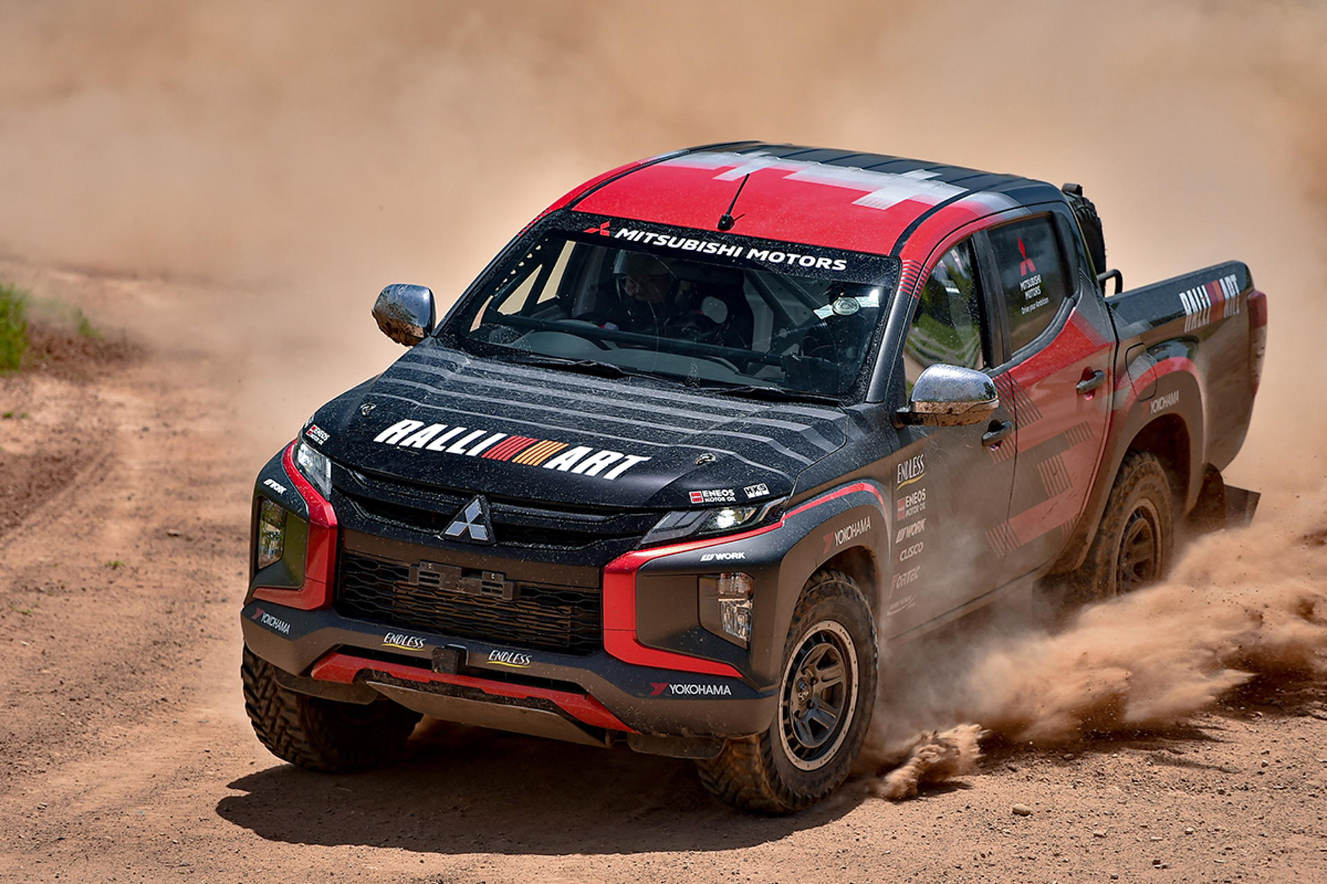 トライトン ラリーカー　“アジアクロスカントリーラリー参戦車（レプリカ）”。トライトン ラリーカーは、2022年11月にタイ～カンボジアで開催されたアジアクロスカントリーラリー（以下AXCR）に参戦して総合優勝を果たしたT1仕様（改造クロスカントリー車両）のレプリカ。ボンネット、前後ドア、内装部品などを軽量化するとともに、ロールケージやアンダーガードを装着するなどボディの要所を補強。専用のサスペンションを装着して優れたハンドリング性能を実現するとともに、前後LSDの採用や大径オフロードタイヤ＆軽量アルミホイールの装着も相まって、悪路走破性を大幅に向上。搭載する2.4リッターディーゼルターボエンジンは、フリクションロスの低減と軽量化を中心としたチューニングにより、ラリーで使用頻度の高い中速域での応答性を向上させた。なお、AXCRのステージには川を渡る場面もあるため、各部のシーリングの強化やシュノーケル（吸気ダクト）の装着など、水回りの対策も行なっている