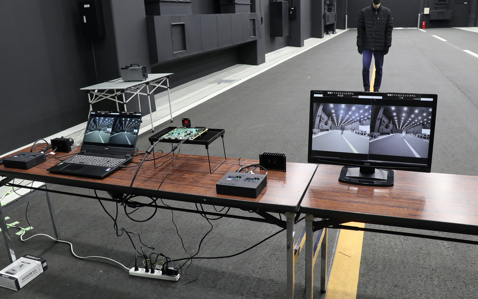環境試験建屋内で実施された「車載ナイトビジョンシステム」のデモ。歩行者役のスタッフは黒いダウンジャケットなど、夜道に溶け込むようなダーク調の服装をあえて着用している