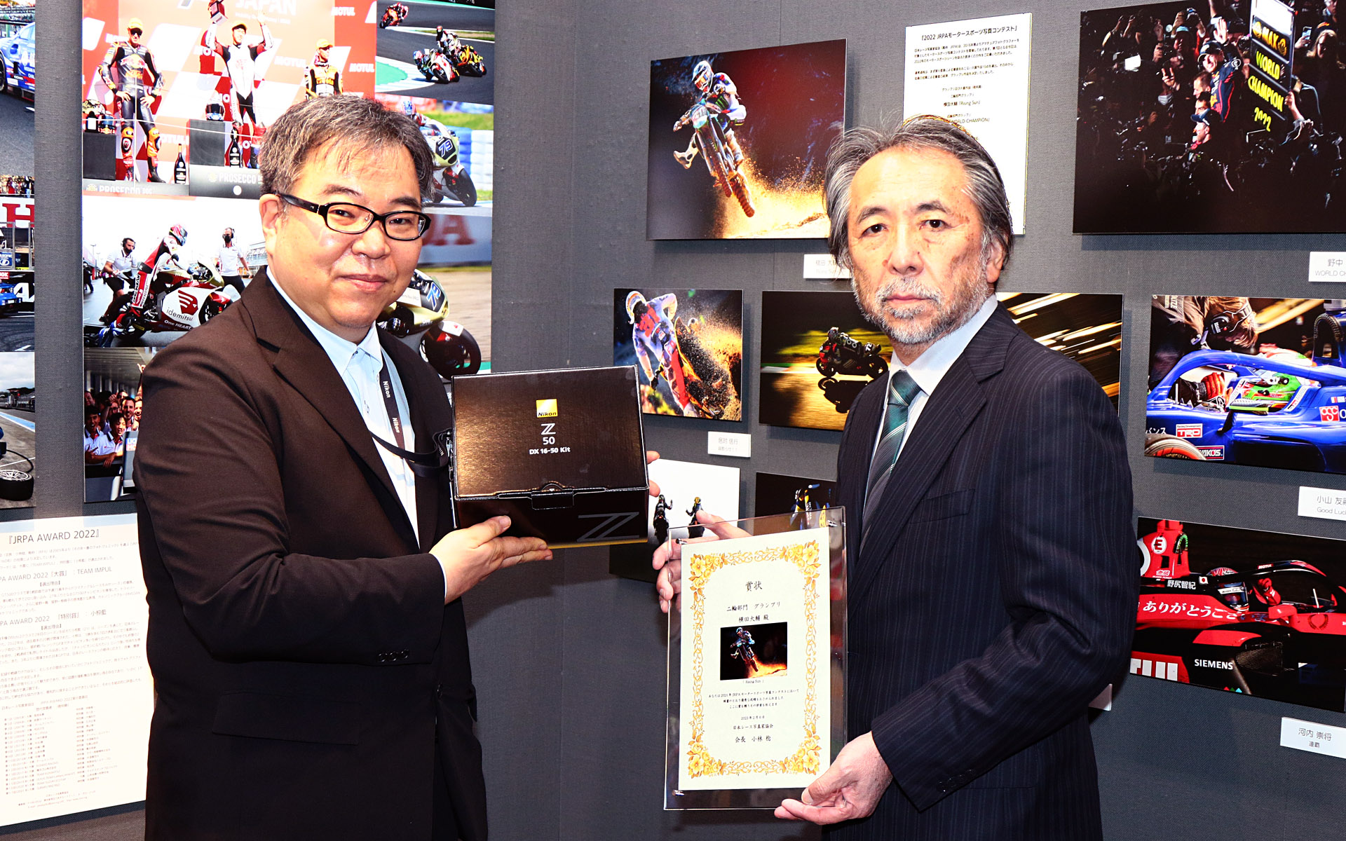 株式会社ニコンイメージングジャパン カスタマーサポート部プロサービス課中島克芳主事（左）より「ニコンZ50 16-50VRレンズキット」がJRPA小林稔会長に手渡された