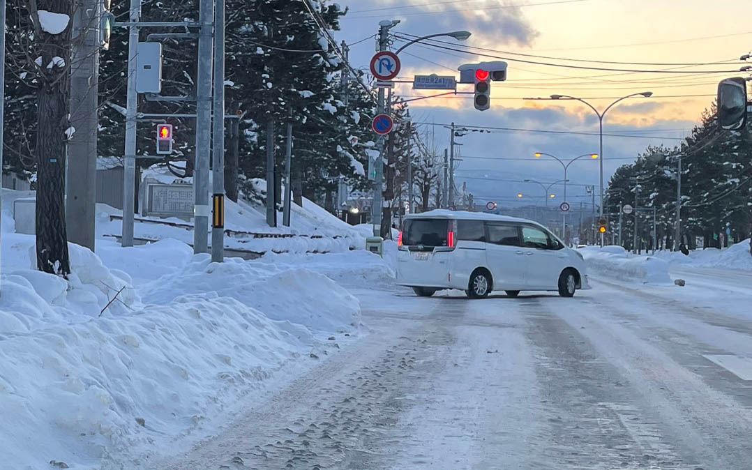 交差点のアイスバーン。黒い轍は路面が磨かれてできた轍。制動と駆動の繰り返しで轍が磨かれていきます