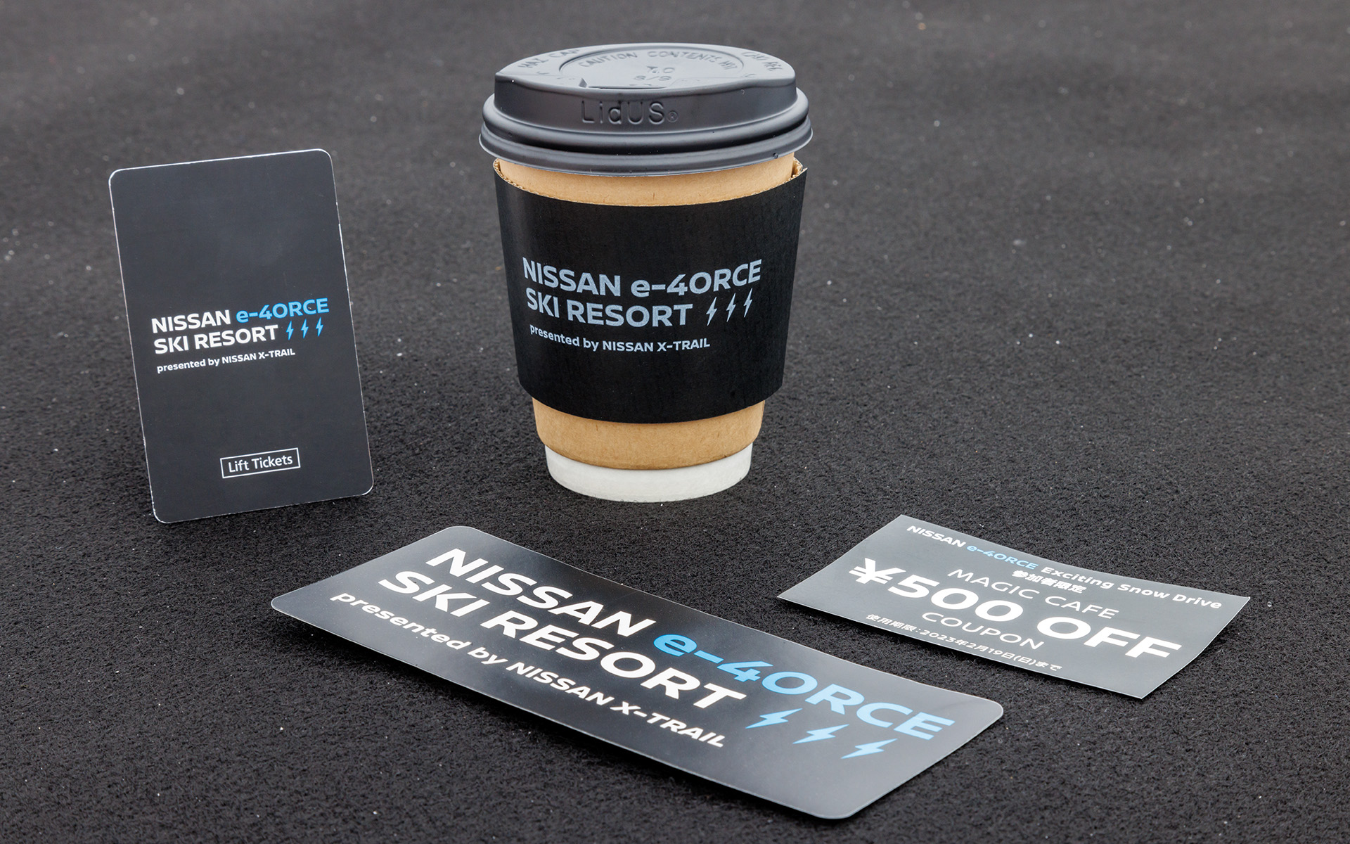 リフト券やドリンクカップもジャック。下はNISSAN e-4ORCE Exciting Snow Drive参加者へのノベルティ