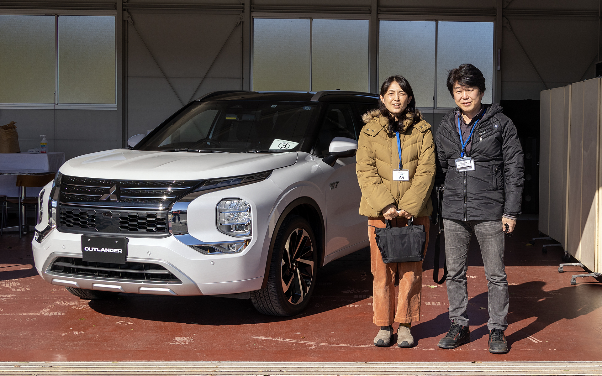 現行型のアウトランダーPHEVを所有する曽我さん。テストコースでお話を伺ったので愛車ではなく展示車と一緒に撮影させていただいた