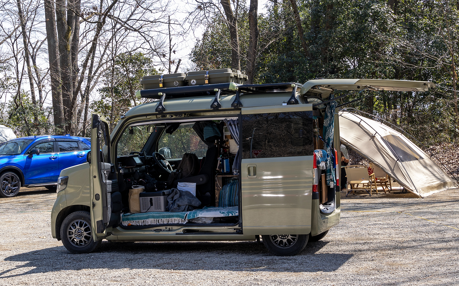 ルーフキャリアは2つ使用。前にはテントなどキャンプ用品をケースに入れて積載。後のキャリアはコンパネにソーラーパネルを固定した太陽光発電も搭載し、室内のポータブルバッテリに充電しているという
