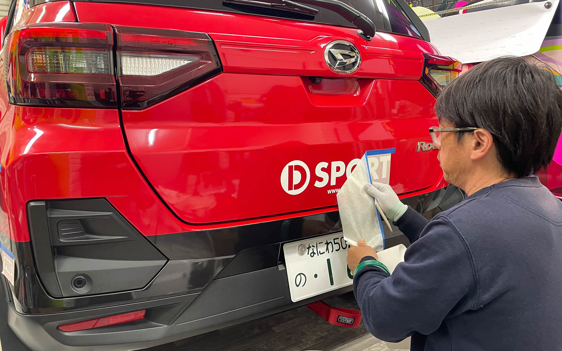 カービューティープロの手によってラリチャレ仕様のラッピングが施されるロッキー。特徴的なコンパーノレッドのボディカラーにラッピングがされたように見えるが、実はブラックのボディカラーの車両をフルラッピングしたという手が込んだ仕様