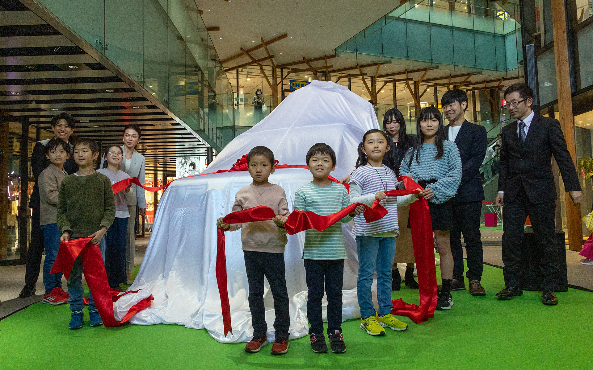 2代目「グリコワゴン」のアンベールは発表会を行った商業施設のフロアにて。グリコワゴンのデザイン公募に応募した子ども達が招かれ、合図と同時にベールに巻かれているリボンを解いた