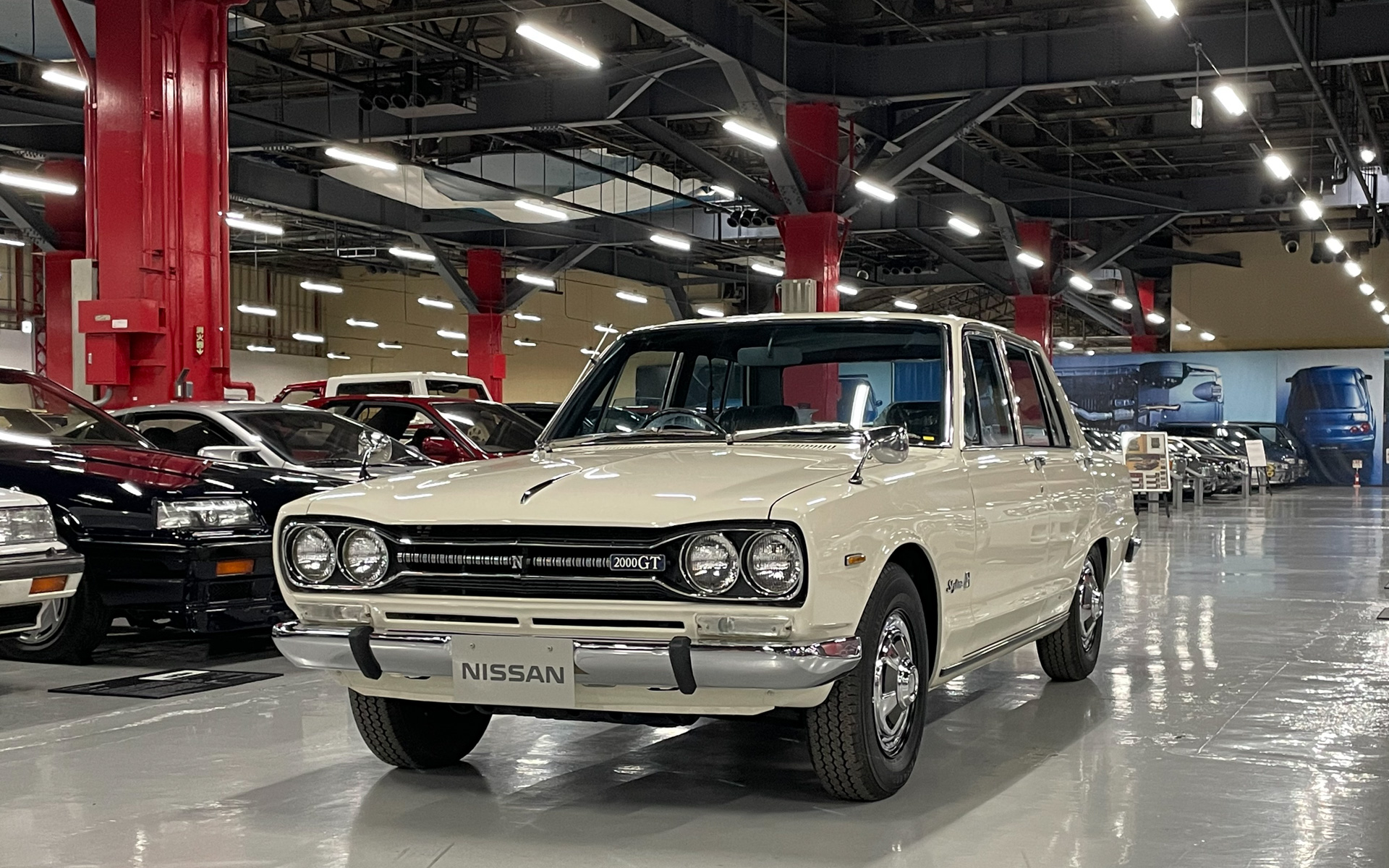 SKYLINE 2000GT：日産・プリンスの合併を経て1968年（昭和43）年に3代目へとフルモデルチェンジしたC10型スカイラインは、後の「ハコスカ」の愛称でも有名。エッジの効いたスタイリングも特徴で、特にリアフェンダーに走るプレスラインは、メーカー自ら流体力学の枠として訴求し、後に「サーフィンライン」の名前で親しまれた。この車両は、2020年に寄贈された個体をベースに、公道での乗車体験実施を意図してフルレストアを進めてきたもので、AUTOMOBILE COUNCILが初公開