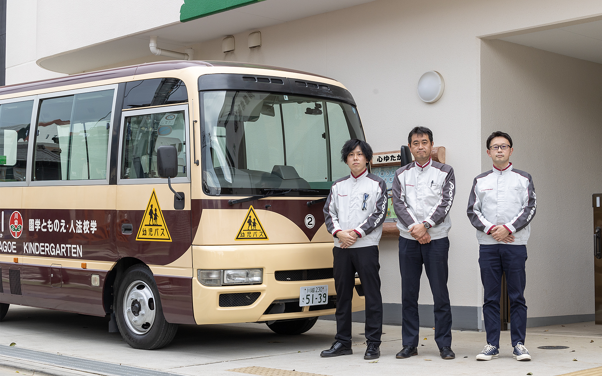NP1特別仕様の実証実験で使用される園児送迎バスと、開発陣であるパイオニア NP1事業本部 プロジェクト推進グループ 商品企画課のメンバー