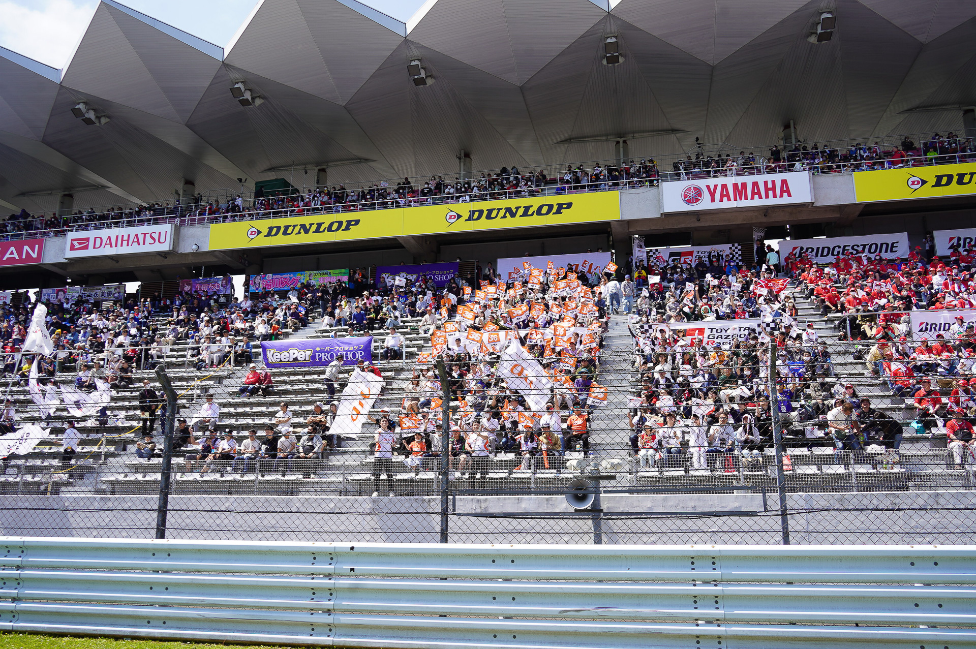 auファンシート。本年から大型のフラッグも導入され、ドライバーからもauファンシートを見つけやすくなったとのこと