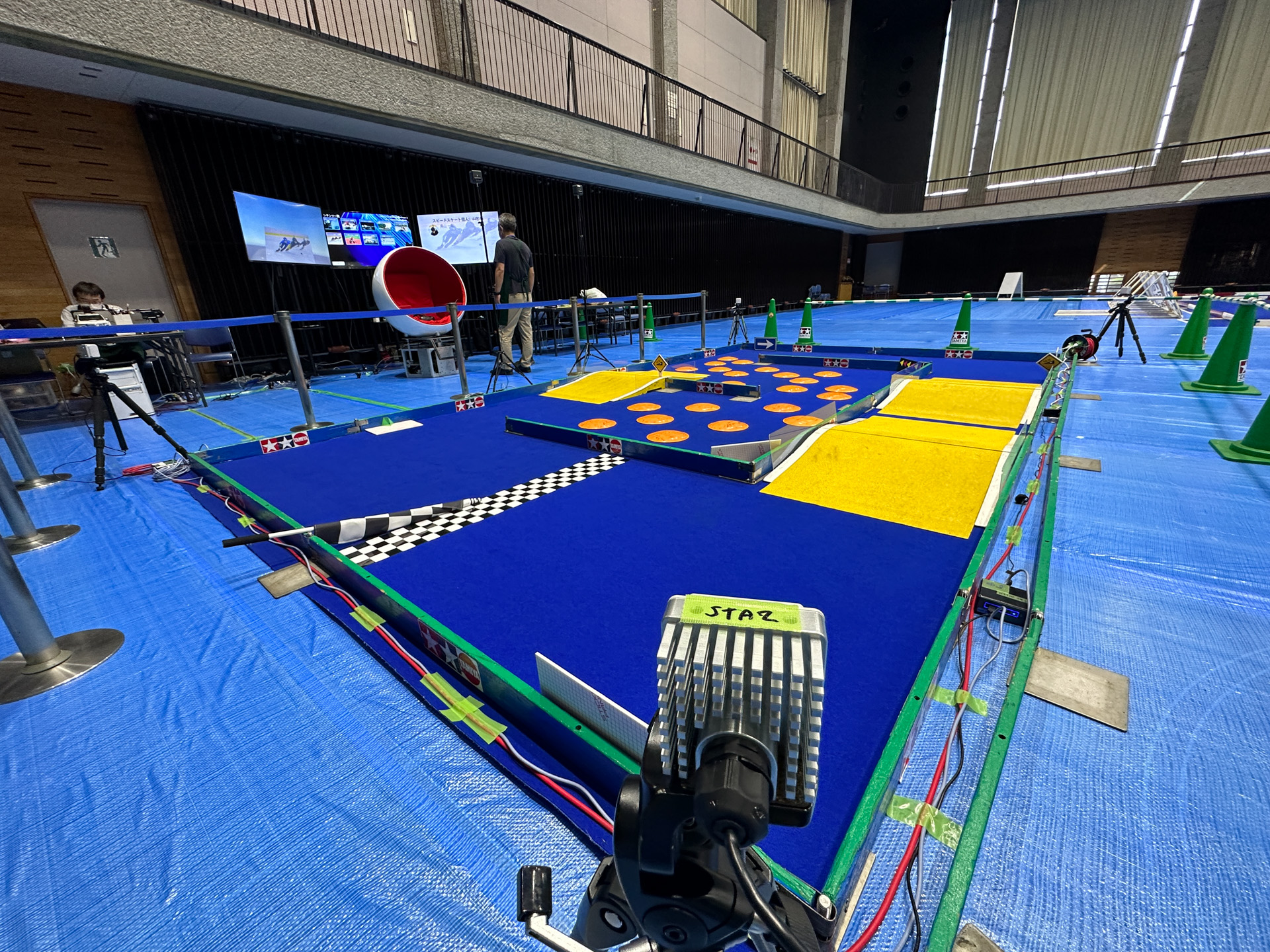 NTTアクセスサービスシステム研究所が研究開発しているサイトダイバーシチ技術とIEEE 802.11ad規格をベースとした60GHz帯を用いる無線LAN規格「WiGig：Wireless Gigabit」を活用。コースの四隅にアンテナが設置された