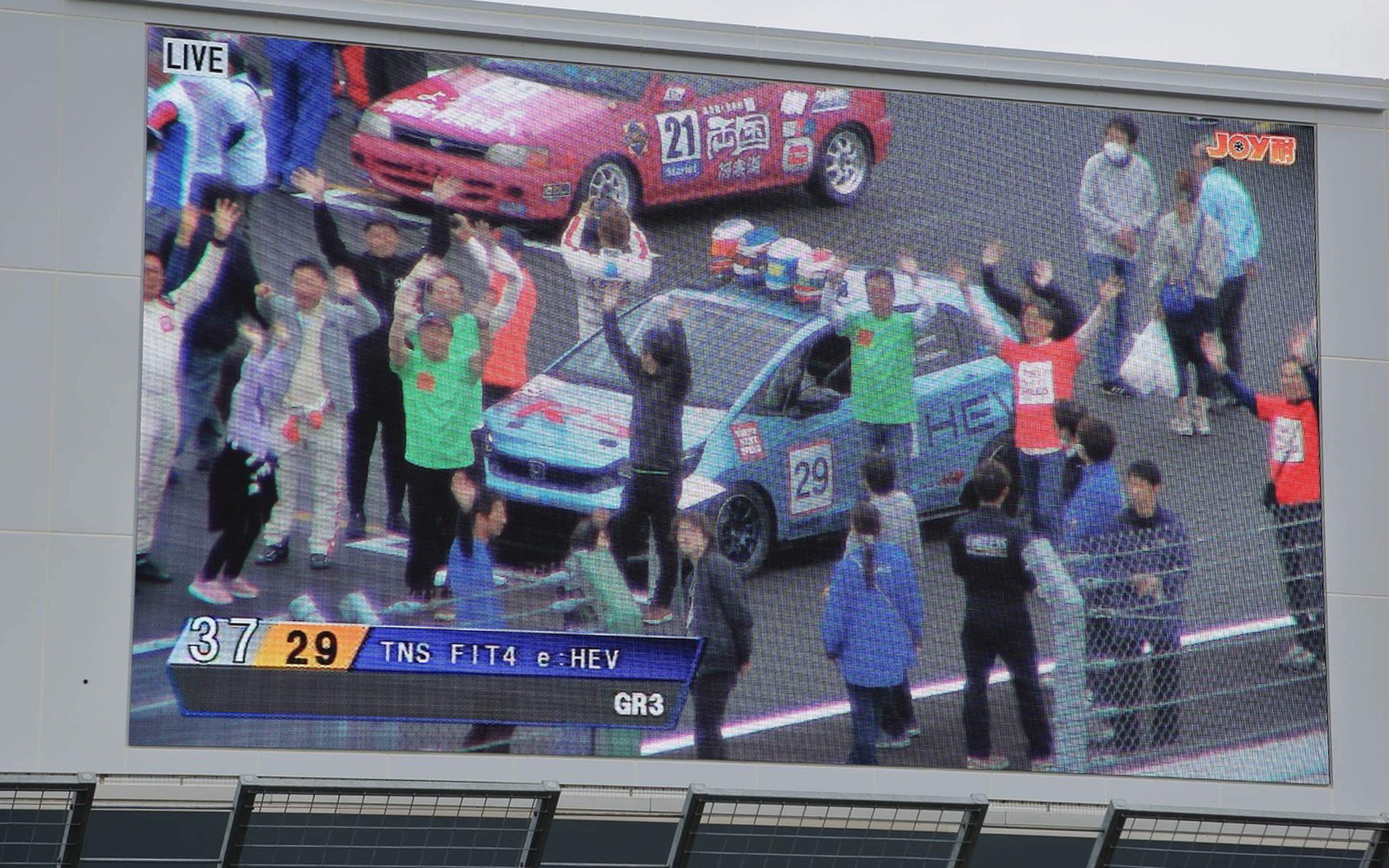 決勝レースのスタート前には、ポールポジションから1台ずつ、こうしてグランドスタンド前の大きなエキシビジョンに映し出されるチーム紹介があるんです。カメラがこちらを映したのを見はからって、みんなで手を振ったりジャンプしたり、大騒ぎするのも楽しいひととき。でも私は見切れてました（笑）