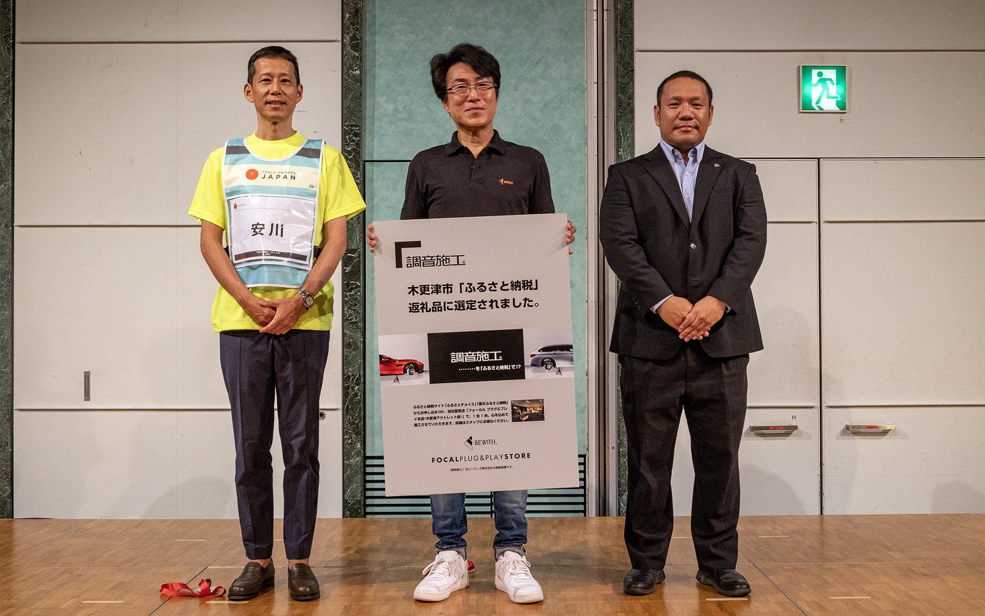 ビーウィズの「調音施工」が木更津市のふるさと納税返礼品に選定され、社団法人テスラ・オーナーズ・クラブ・ジャパン主催の「2023TOCJ 全国ミーティング」で発表を行なった。左から社団法人テスラ・オーナーズ・クラブ・ジャパン代表の安川洋氏、ビーウィズ株式会社 代表取締役 中島敏晴氏、木更津市財務部財政課 池田氏