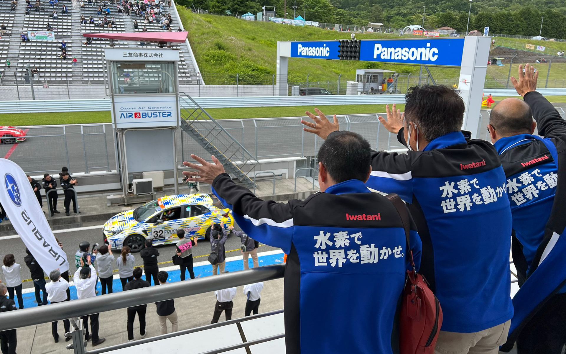 ピットピルの2階からゴールした32号車 液水カローラに手を振る岩谷産業スタッフ。「水素で世界を動かせ。」ジャケットの下は、「水素で世界を動かせ。」シャツだった
