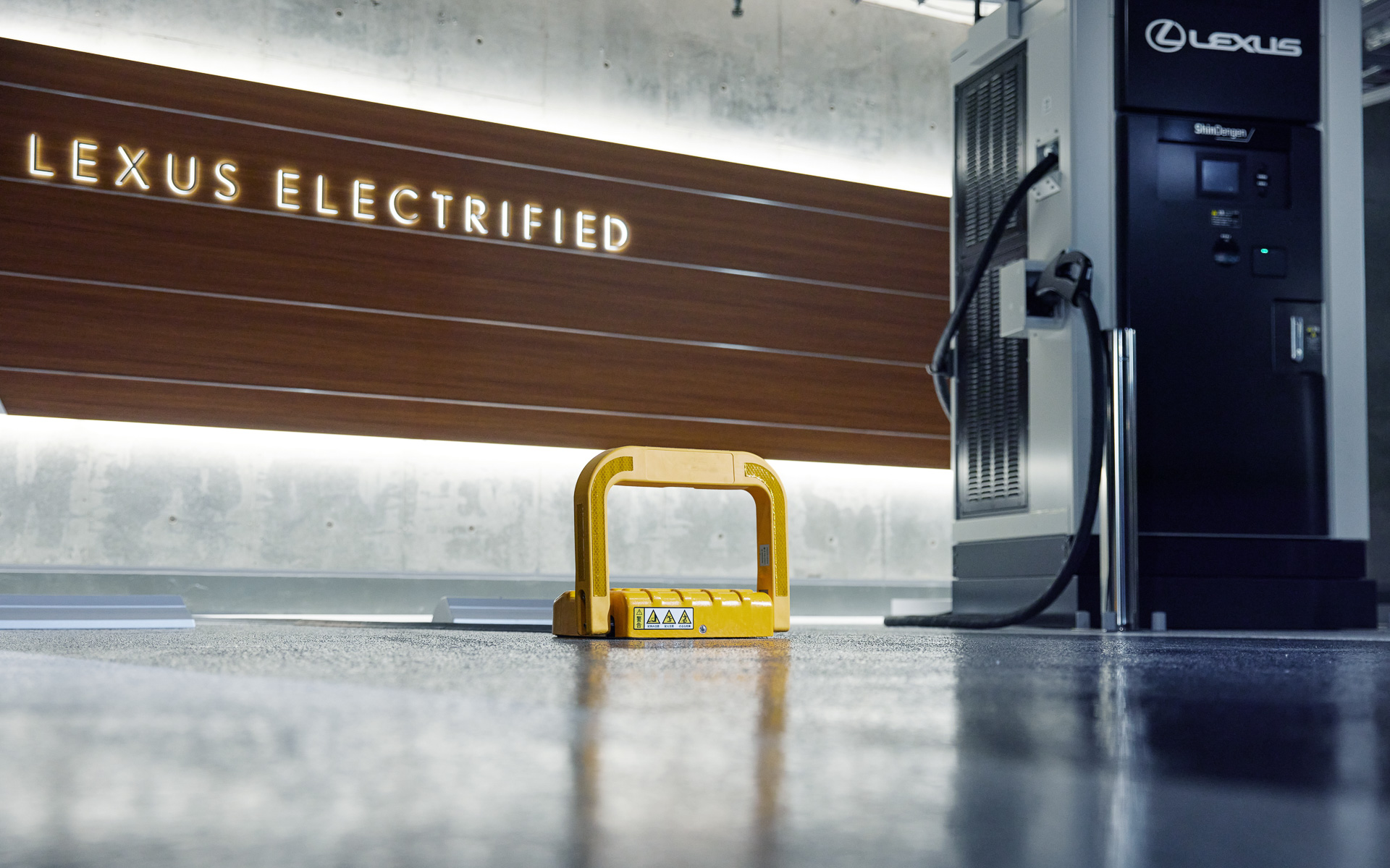 レクサス充電ステーションの駐車場所にある黄色いスタンド。予約者が近づくと自動的にスタンドは下がる