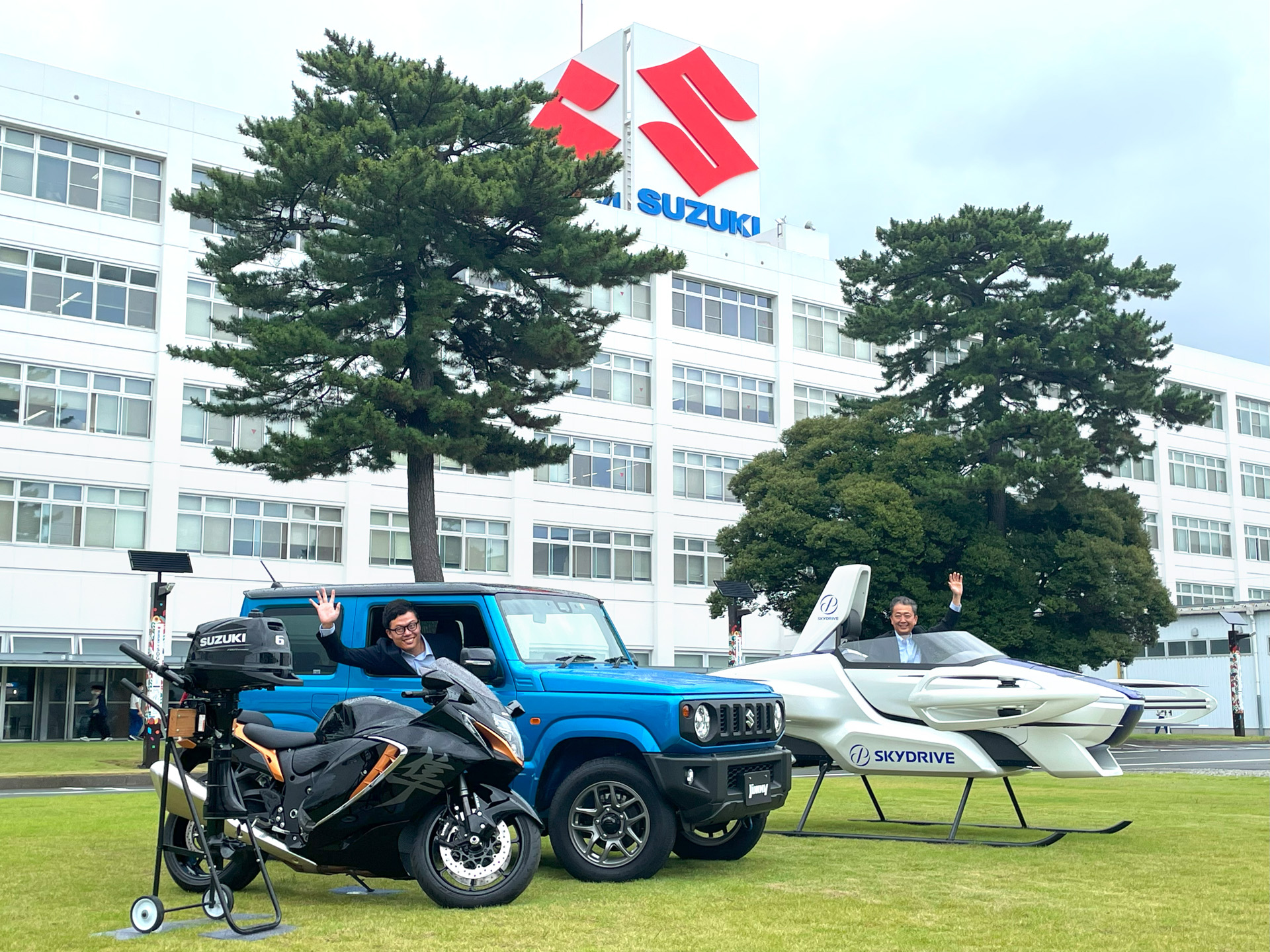 左からスズキの船外機、隼（Hayabusa）、ジムニー、SkyDriveのSD-03 スケールモデル、ジムニーにSkyDrive代表取締役の福澤知浩氏、SD-03 にスズキ常務役員 神代英俊氏