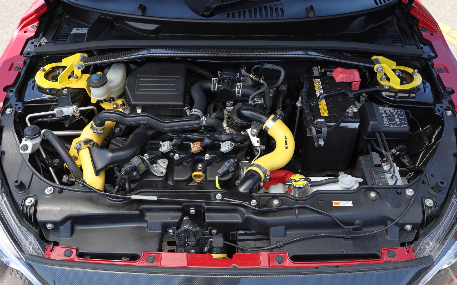 フロントまわりの剛性を高める「ストラットタワーバー（アルカーボンオーバル）」の価格は1万9800円。ブレーキのタッチを向上させる「ブレーキマスターシリンダーストッパー」は1万7600円。また、純正吸気ラインと置換することで吸気効率を向上させ、レスポンスアップに寄与するスーパーインテークホースキット（5万8300円）を装着している