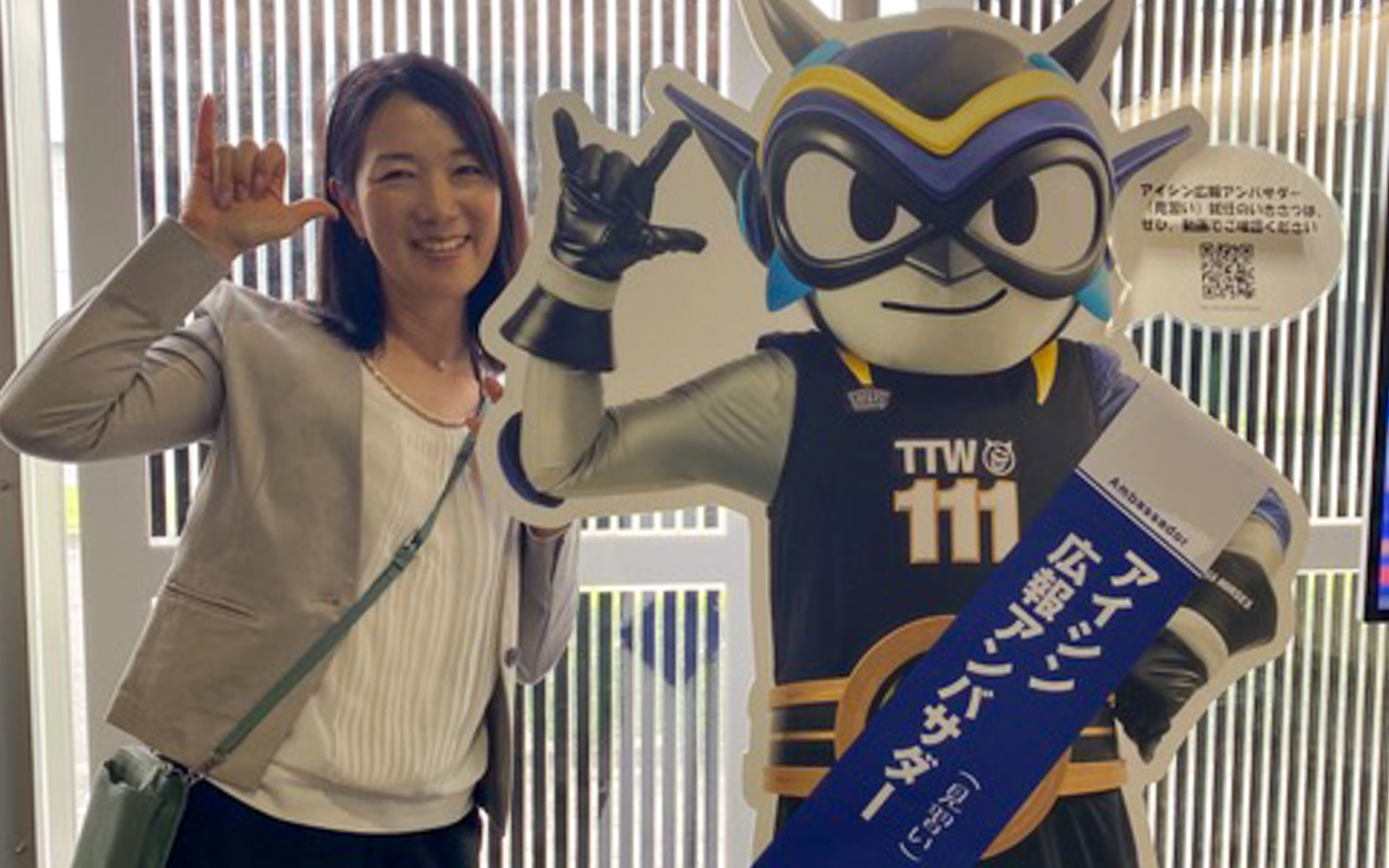 愛知県刈谷市にあるアイシン本社隣接の「コムセンター」に入ると、左手にちょっと目立つ人の姿が（笑）。こちらは2022年1月にアイシン広報アンバサダー（見習い）として任命され、認知拡大のために活動している「タツヲ」さん。アイシンがサポートしているプロバスケットボールチーム「シーホース三河」所属のタレントさんだそうで、背番号は三河にちなんで「111」をつけています。私も小・中とバスケ部出身なので、親近感が湧きました